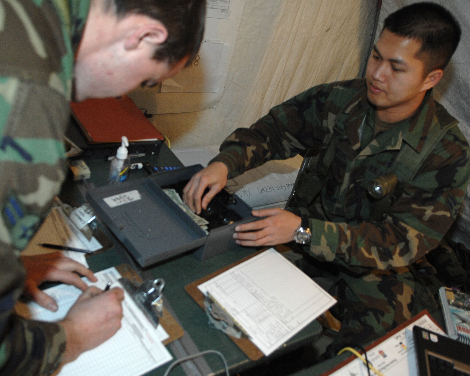 MOUNTAIN HOME AIR FORCE BASE, Idaho-- Airman 1st Class Arckay Santos, 366th Services Squadron food service specialist, operates the cash register in the deployed dining facility while Senior Airman Paul Wood, 366th Operation Support Squadron aircrew flight technician, signs in on the food services sign in sheet during Exercise Coronet White 08-ACC-14 March 16. The 366th Fighter Wing is participating in an Operational Readiness Inspection March 13-21 to test the wing's ability to deploy and take its mission to war. (U.S. Air Force photo by Airman 1st Class Stephany Miller) 