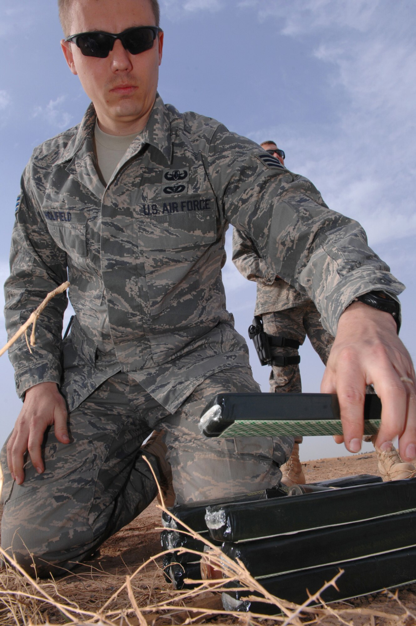BALAD AIR BASE, Iraq -- Senior Airman Stephen Holifield, 332nd Expeditionary Civil Engineer Squadron explosive ordnance disposal technician, places C-4, an explosive substance, on top of unexploded ordnances to create a controlled detonation here, March 13. Unexploded ordnances that have been collected from indirect fire attacks must be blown up to prevent them from reentering opposing forces' hands. Airman Holifield is deployed from Hurlburt Field, Fla. (U.S. Air Force photo/ Senior Airman Julianne Showalter)