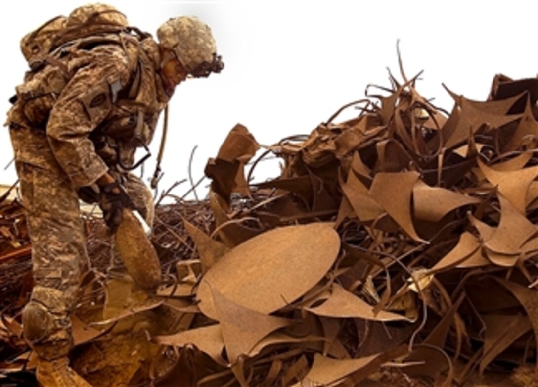 U.S. Army Sgt. Philip Dukett  removes a rusted mortar round from a pile of scrap metal, March  11, 2008, at a junkyard north of Camp Taji, northwest of Baghdad. Dukett is an infantryman assigned to the 25th Infantry Division's Company B, 14th Infantry Regiment, 2nd Stryker Brigade Combat Team.