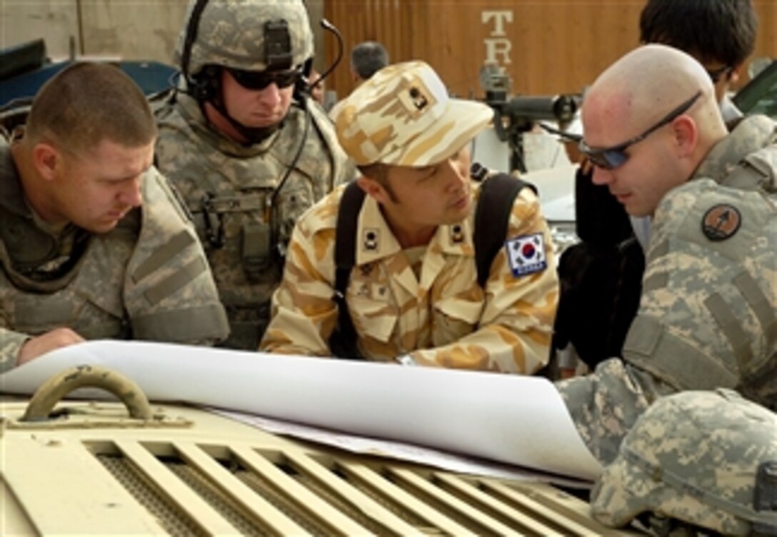 U.S. Army Capt. Robert Day, far right, discusses route plans with a Korean army liaison officer concerning convoy security while Sgt. Matthew D. Chance, far left, and Sgt. 1st Class Alan L. Sutton look on in Baghdad, March 13, 2008. The soldiers are assigned to Headquarters Support Company, Task Force Dragon, and Day is the commander.