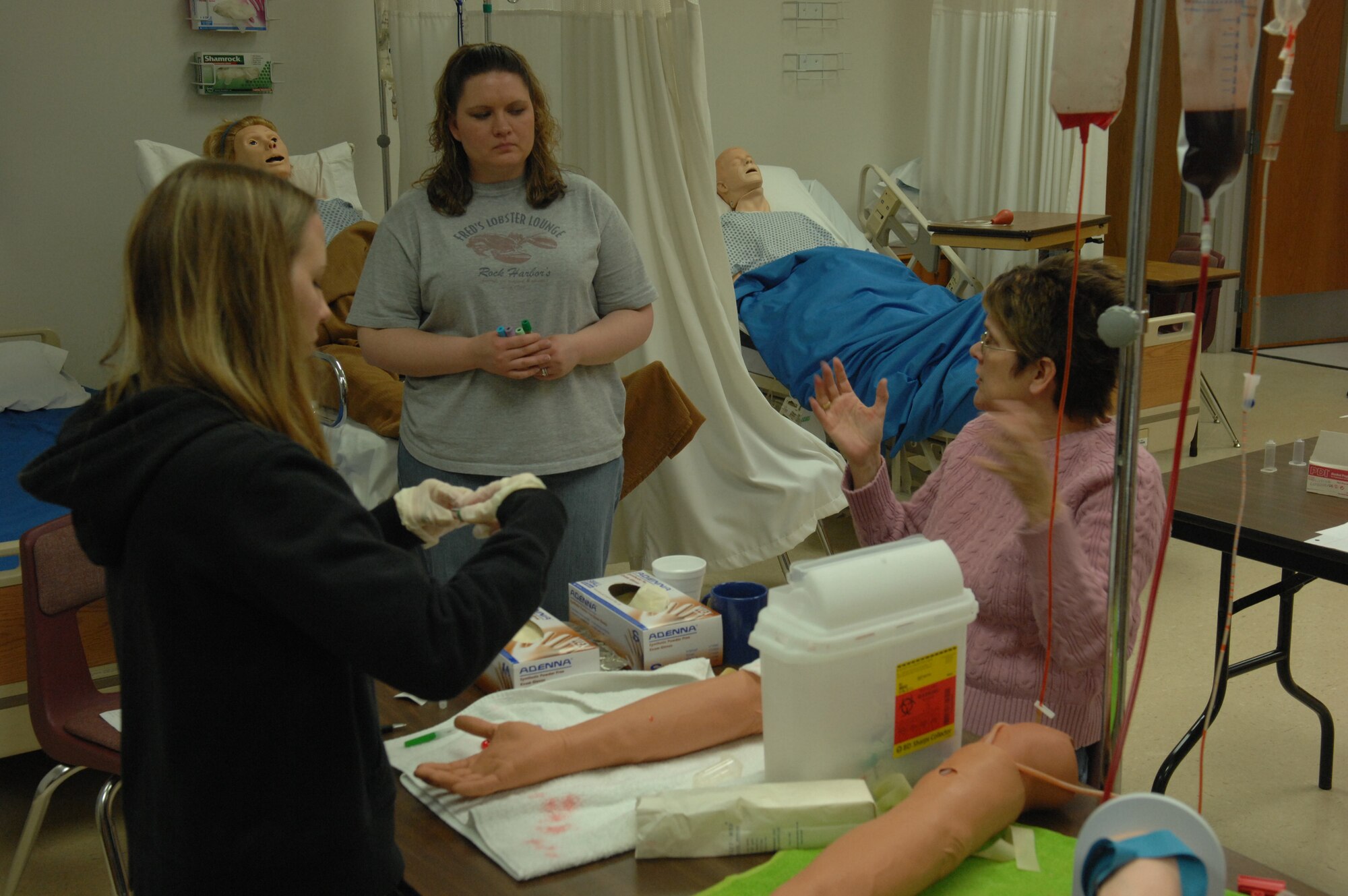 (Right)Terri Rostad, Western Dakota Technical Institute instructor explains the right procedures for inserting a butterfly needle into a patient to her students at Western Dakota Technical Institute March 13. The students are learning required techniques to graduate the Licensed Practical Nurse program. Members of the LPN program will begin clinical training March 31 at the 28th Medical Group clinic on Ellsworth. (U.S. Air Force photo/Airman 1st Class Adam Grant)
