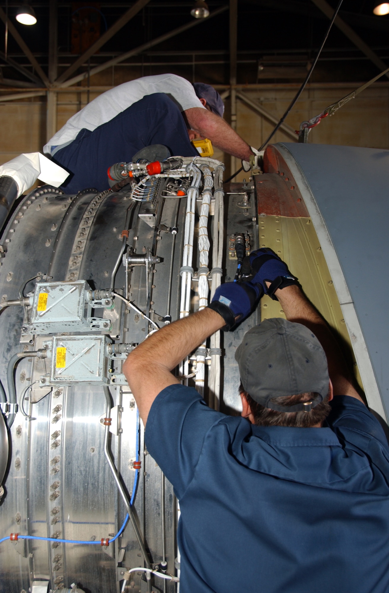 ALTUS AIR FORCE BASE, Okla. -- From top, 97th Tanker Sortie Generation Engine Mechanics Kim Cather and Barry Coffey bolt on the engine ring cowl before installing the engine at Hangar 523 March 14. (Photo by Senior Airman Clinton Atkins)