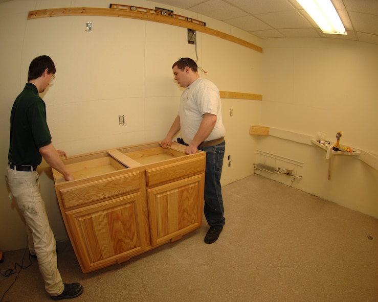 MINOT AIR FORCE BASE, ND -- Casey Emerick, Burdick Job corps carpentry student, and Travis Hudson, a shop manager and facility maintenance student, install a cabinet in a base dormitory here March 14. Students from Job Corps volunteered their time to build kitchens in several of the base dorms. (U.S. Air Force photo by Airman 1st Class Sharida Bishop)