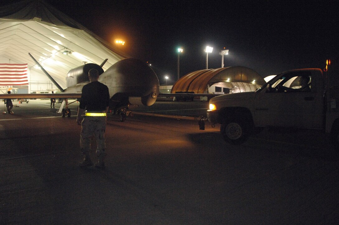 Members of the 380th Expeditionary Aircraft Maintenance Squadron back an RQ-4 Global Hawk unmanned aerial system into a hanger after a mission March 11in Southwest Asia. The 380th Air Expeditionary Wing has been an integral part in the Global Hawk recently reaching its 10 year and 20,000 flight hour milestones. (U.S. Air Force photo/Senior Airman Levi Riendeau)