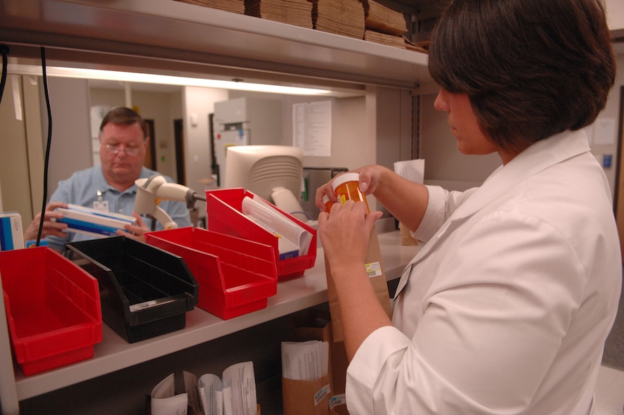 MOODY AIR FORCE BASE, Ga. -- A student pharmacist grabs ready prescriptions for patients after John Anderson,a civilian registered pharmacist, verifies the prescriptions contents here March 18. The Moody pharmacy double checks prescriptions to ensure there are no counting errors and the correct tablets are provided. (U.S. Air Force photo by Senior Airman Gina Chiaverotti)