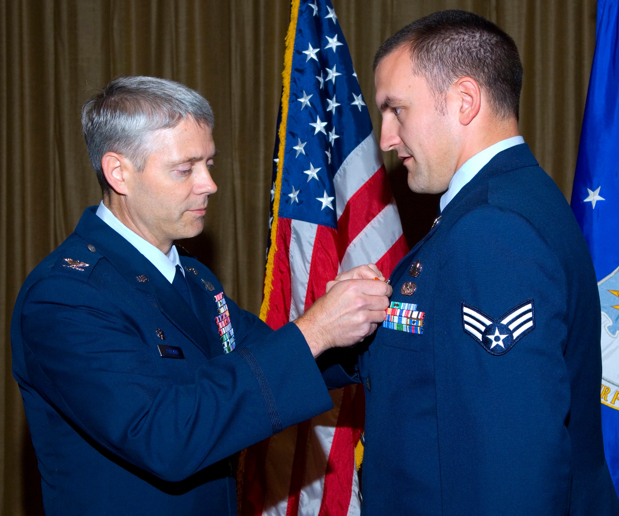 Col. Eric Pohland, 96th Air Base Wing commander, pins a Combat Action Medal on Senior Airman Daniel Garrett, 96th Civil Engineer Squadron's Explosive Ordnance Disposal Flight.  Airman Garrett was part of a team that responded to an explosive device blast while operating north of Baghdad, Iraq.  They assisted injured Airmen, secured the scene and detonated a secondary IED.The award is for Airmen who have been involved in direct fighting situations where they risked their lives in an enemy engagement. 