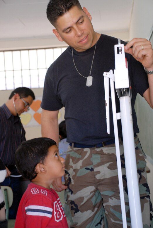 SOTO CANO AIR BASE, Honduras--Air Force Staff Sgt. Abe Alcivar, MEDEL medical equipment technician, weighs a young Honduran boy during the Morolica MEDRETE March. 10. Sergeant Alcivar was one of the MEDEL staff used as a translator during the triage process.  (U.S. Air Force photo by Tech. Sgt. William Farrow)