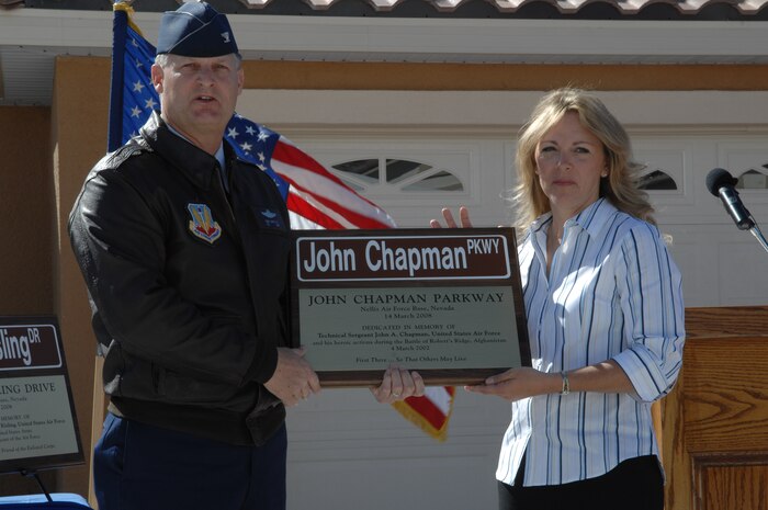 NELLIS AIR FORCE BASE, Nev. -- Col. Michael Bartley, 99th Air Base Wing commander, and Valerie Chapman display a plaque commemorating the dedication of a street in The Landings at Nellis housing area for her husband, Tech. Sgt. John A. Chapman.  Sergeant Chapman, a combat controller, was posthumously awarded the Air Force Cross for his heroic actions in combat against Al Qaeda forces near Gardez, Afghanistan on March 4, 2002.  (U.S. Air Force photo by Senior Airman Nadine Barclay)