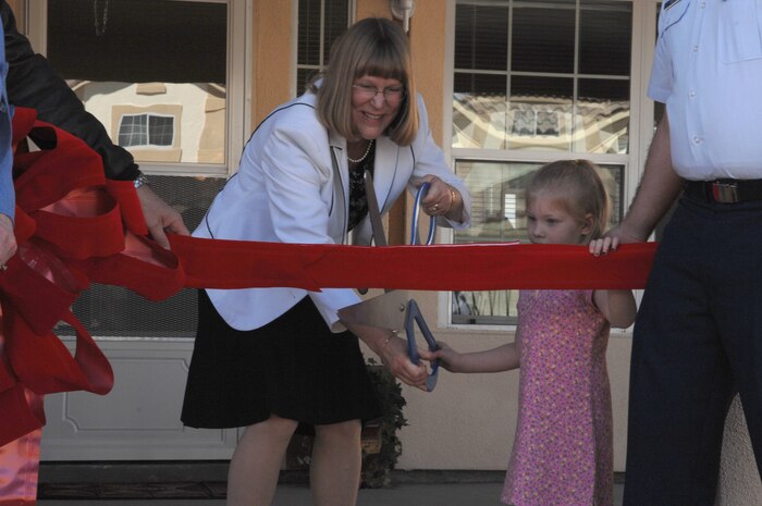 NELLIS AIR FORCE BASE, Nev. -- Karen Apple and Juliana Ollis cut the ribbon to dedicate the first house in The Landings at Nellis military family housing area.  Mrs. Apple, daughter of the third Chief Master Sgt. of the Air Force Richard D. Kisling, cut the ribbon to open the original houses in the area in 1960 when her family became the first occupants of the then-new housing known as Manch Manor.  Juliana is the daughter of Senior Airman Nathan and Caitlin Ollis.  The Ollis' are the first family to move into the new homes at The Landings at Nellis. (U.S. Air Force photo by Senior Airman Nadine Barclay)