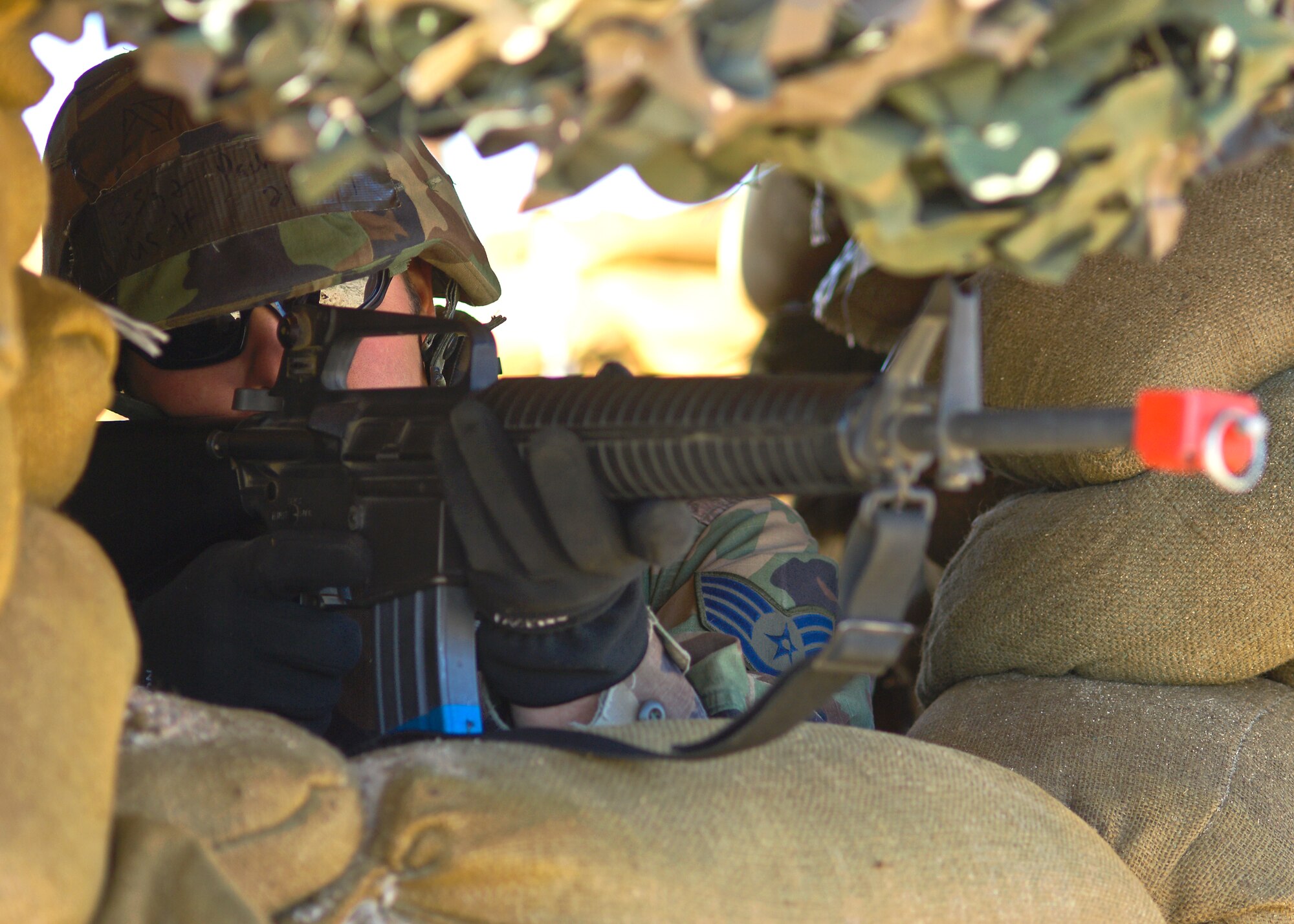 An Edwards Airman aims an M-16 assault rifle from a bunker during the base's Operational Readiness Exercise Phase II exercises at Camp Corum here March 12. Edwards held the ORE to test the base's ability to deploy Airmen downrange and then the Airmen's ability to survive and operate in a deployed location.  (Air Force photo by Mike Cassidy)