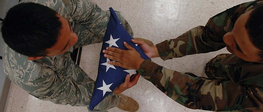 MOODY AIR FORCE BASE, Ga. -- Airman 1st Class Larry Best (right), 23rd Wing Honor Guard red flight member, presents a folded flag to a mock family member during a practice for an upcoming retired service member's funeral. During the funeral a seven-man team will fold the flag 13 times before presenting it to the family of the deceased. (U.S. Air Force photo by Airman 1st Class Brittany Barker)