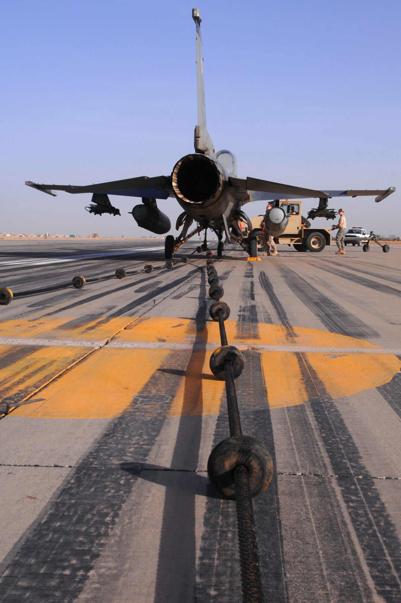 An F-16 Fighting Falcon waits to be disconnected from an emergency arresting barrier system cable after passing a certification test of the system March 16 at Balad Air Base, Iraq. The system was installed by the 332nd Expeditionary Civil Engineer Squadron and is used to bring fighter aircraft to a smooth halt during emergency landings. (U.S. Air Force photo/Senior Airman Julianne Showalter) 