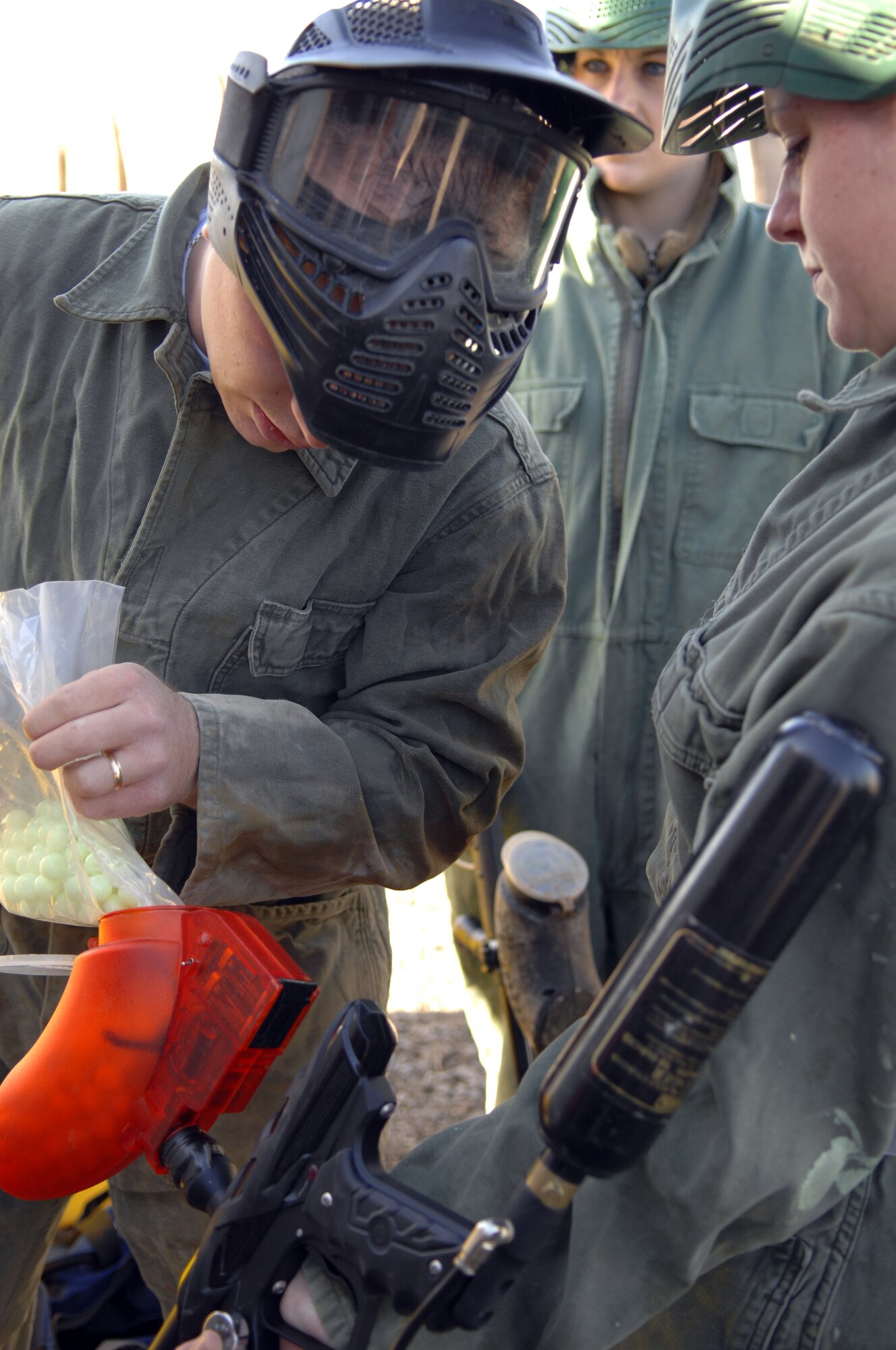 Airman 1st Class Brandon Humes, 49th Security Forces Squadron, assists Airman 1st Class Leah Weh, 49 SFS, in pouring paintballs into her paintball gun at the Apache Range on Holloman Air Force Base, N.M., March 14. The Airmen were participating in a team-building game of paintball as a part of Service’s Day. (U.S. Air Force photo/Airman Sondra Wieseler)
