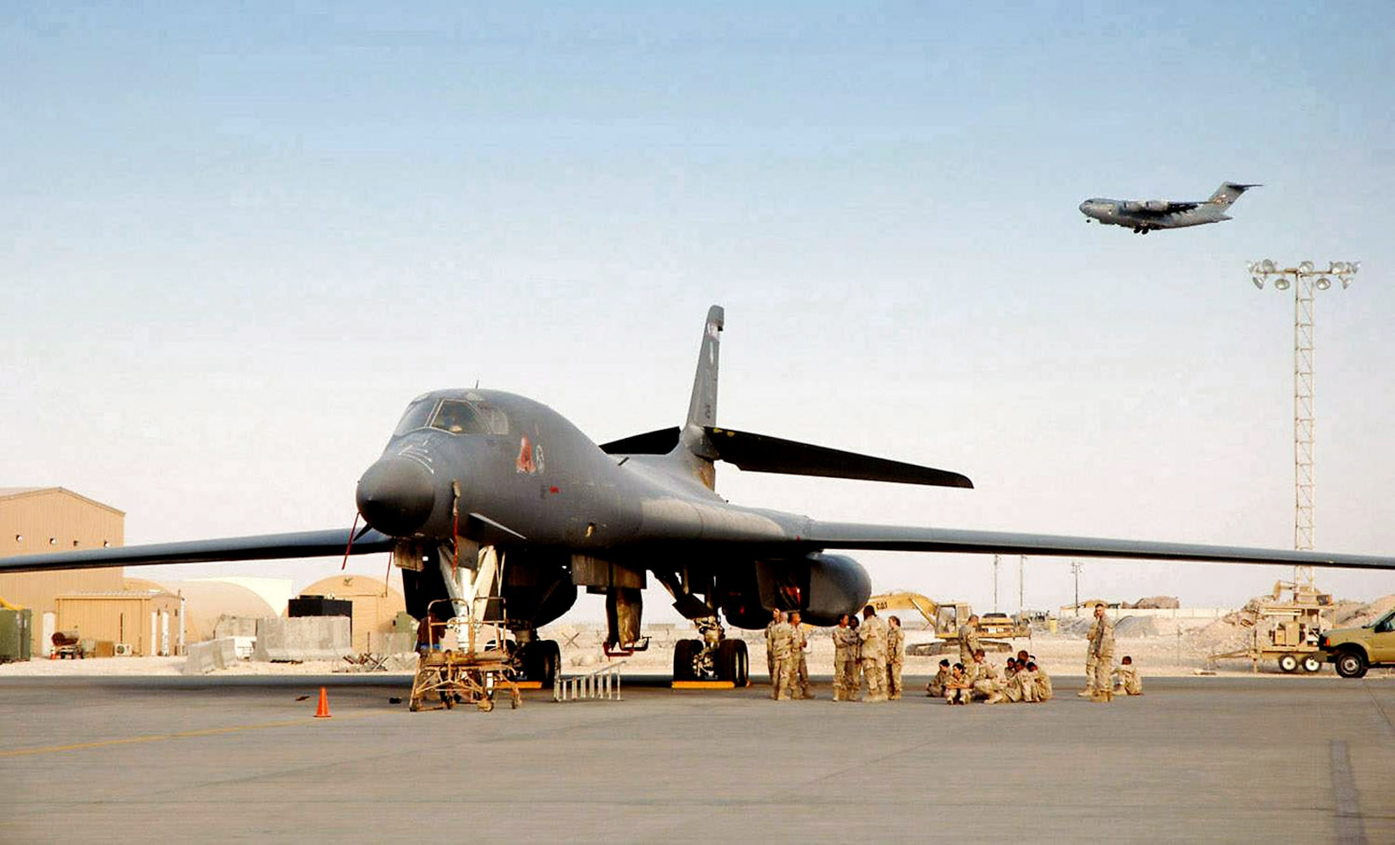 Maintainers ensure this B-1B Lancer is ready to go as a C-17 Globemaster III prepares to land at a forward deployed location in Southwest Asia. (U.S. Air Force photo/Master Sgt. Ken Stephens) 
