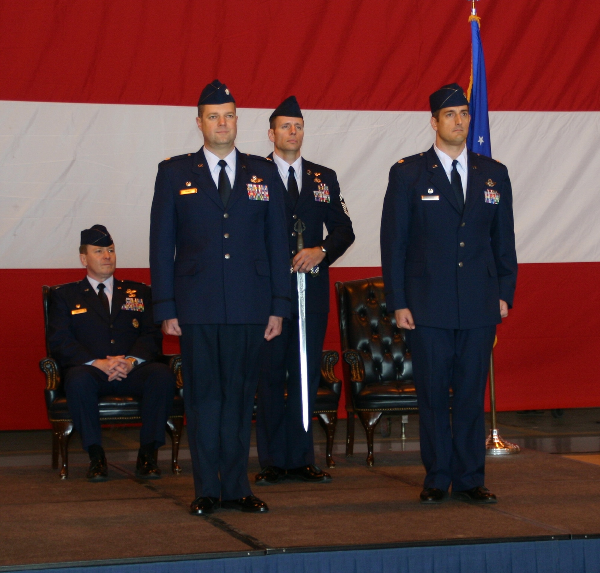 Lt. Col. John T. Russell, 963rd AACS, commander, prepares to pass the traditional Blue Knights' sword over to Lt. Col. Robert M. Haines, who accepted command of the squadron March 7 in a change of command ceremony officiated by Col. Christof P. Cordes, 552nd Operations Group, commander (seated).