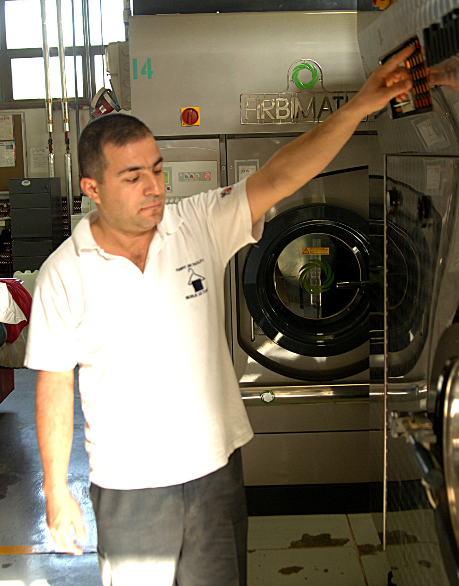An employee with the 39th Services Squadron fabric care facility operates the new Earth-friendly dry-cleaning machine. The machine was rebuilt from an old machine that used an environmentally "unfriendly" solvent. The new machine uses a new solvent that is better for the environment. (U.S. Air Force photo by Senior Airman Heather Stanton)