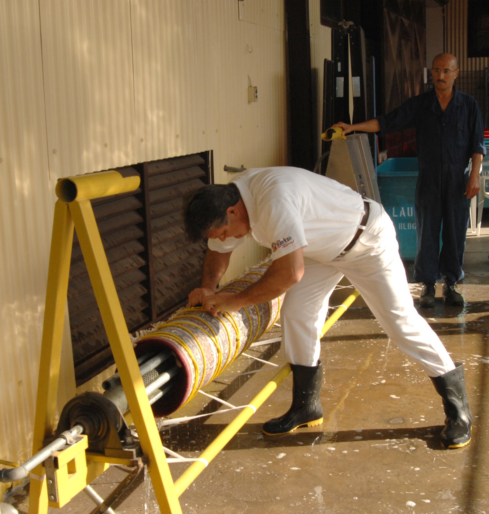 An employee at the 39th Services Squadron fabric care facility tightens a carpet on the carpet rinsing and drying machine, which was designed and built by one of their own. The new machine reduces the turn-around time of carpets from five days to just two days. (U.S. Air Force photo by Senior Airman Heather Stanton)