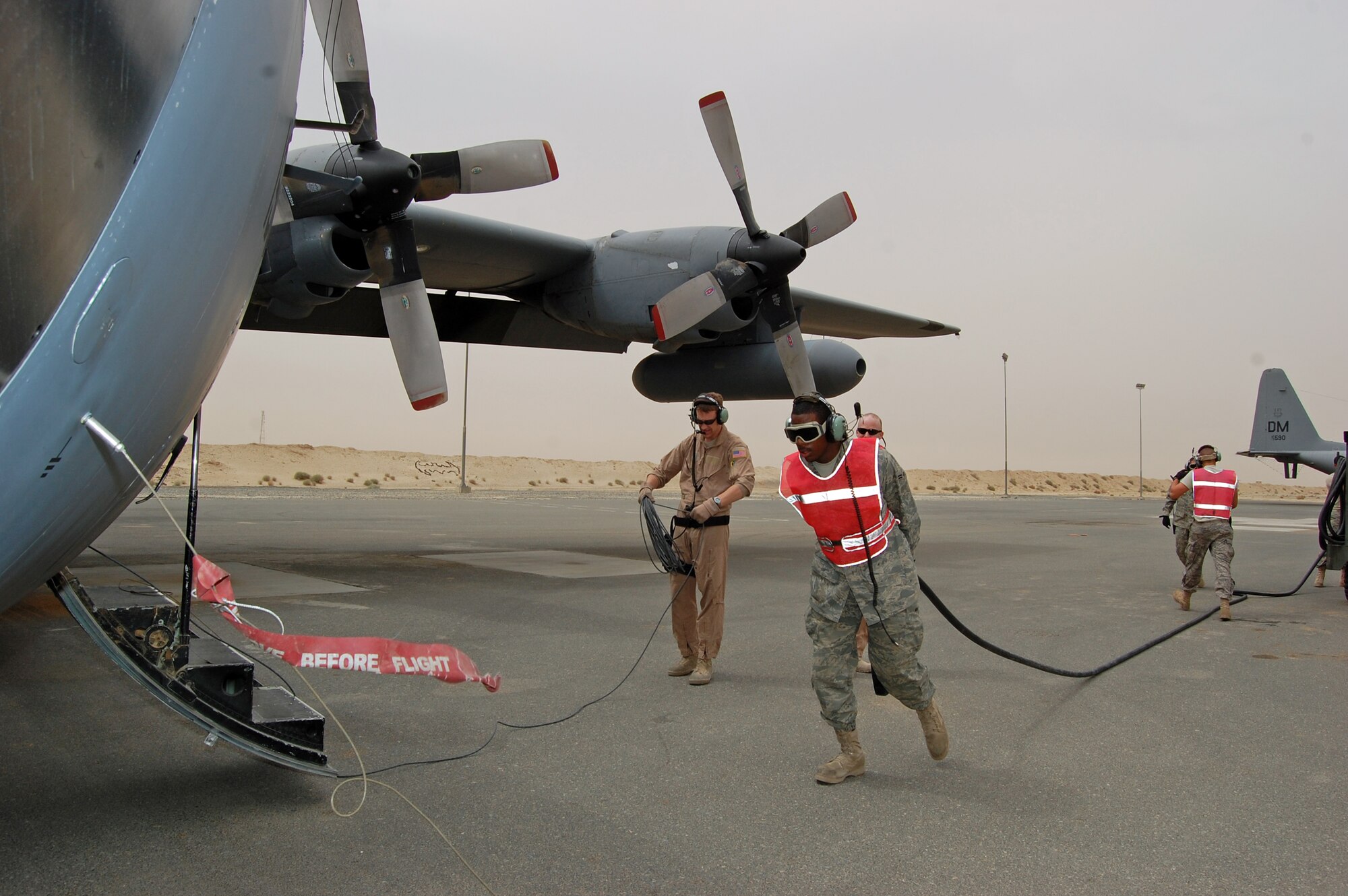 SOUTHWEST ASIA -- Airman 1st Class Rashaud Johnson, a C-130 electronic counter measure specialist deployed with the 386th Expeditionary Aircraft Maintenance Squadron drags an external power source from a maintenance cart to an EC-130H Compass Call aircraft while other aircrew and ground personnel accomplish other aspects of the post-flight inspection at an air base in the Persian Gulf Region March 18, 2008. Airman Johnson is deployed from the 755th AMXS, out of Davis-Monthan Air Force Base, Ariz., supporting the Global War on Terror. (Air Force photo/Tech. Sgt. Michael O’Connor)