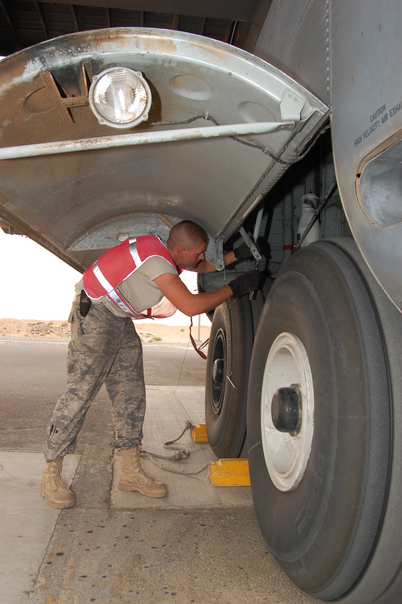 SOUTHWEST ASIA -- Airman Cory Francis, a C-130 crewchief deployed with the 386th Expeditionary Aircraft Maintenance Squadron attaches a hinge pin to a rod which holds open the main landing gear door on an EC-130H Compass Call aircraft at an air base in the Persian Gulf Region March 18, 2008. Airman Francis is deployed from the 755th AMXS, out of Davis-Monthan Air Force Base, Ariz., and a part of his duties is to conduct post-flight inspections of aircraft supporting the Global War on Terror. (Air Force photo/Tech. Sgt. Michael O’Connor)