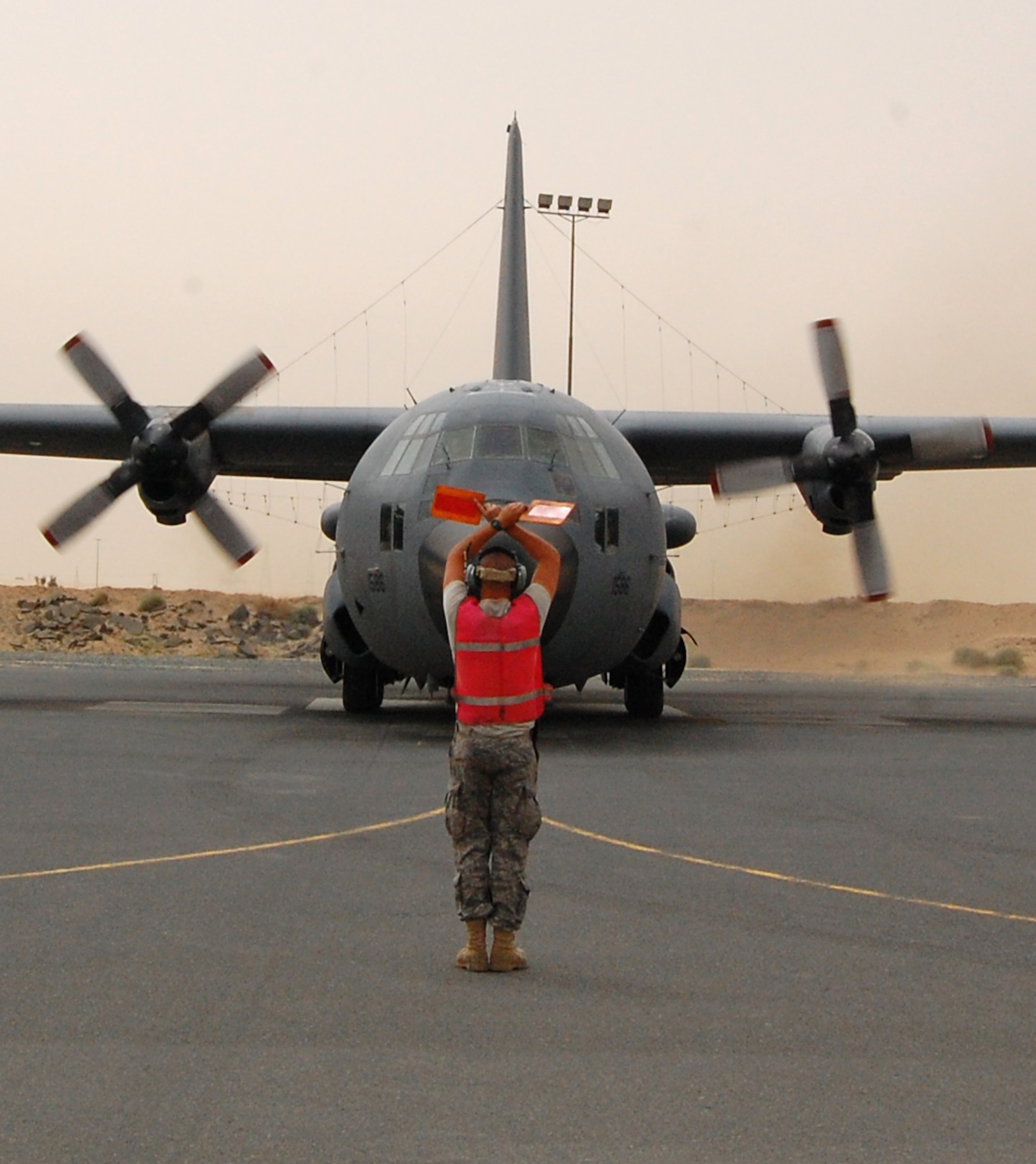 SOUTHWEST ASIA -- Airman Cory Francis, a C-130 crewchief deployed with the 386th Expeditionary Aircraft Maintenance Squadron gives the 'stop movement commmand' with his marshalling paddles to aircraft commander Capt. Tony Stibral and co-pilot 1st Lt. Corey Hogue returning from a mission March 18, 2008, as they back into their parking spot on the ramp of an air base in the Persian Gulf Region. The pilots and seven other crewmembers from the 43rd Expeditionary Electronic Combat Squadron on board completed the unit’s 2,276th combat sortie capping the Arizona-based unit’s fourth consecutive year deployed supporting the Global War on Terror. Airman Francis is deployed from the 755th AMXS, and the aircrew members from the 55th Electronic Combat Group out of Davis-Monthan Air Force Base. (Air Force photo/Tech. Sgt. Michael O’Connor)