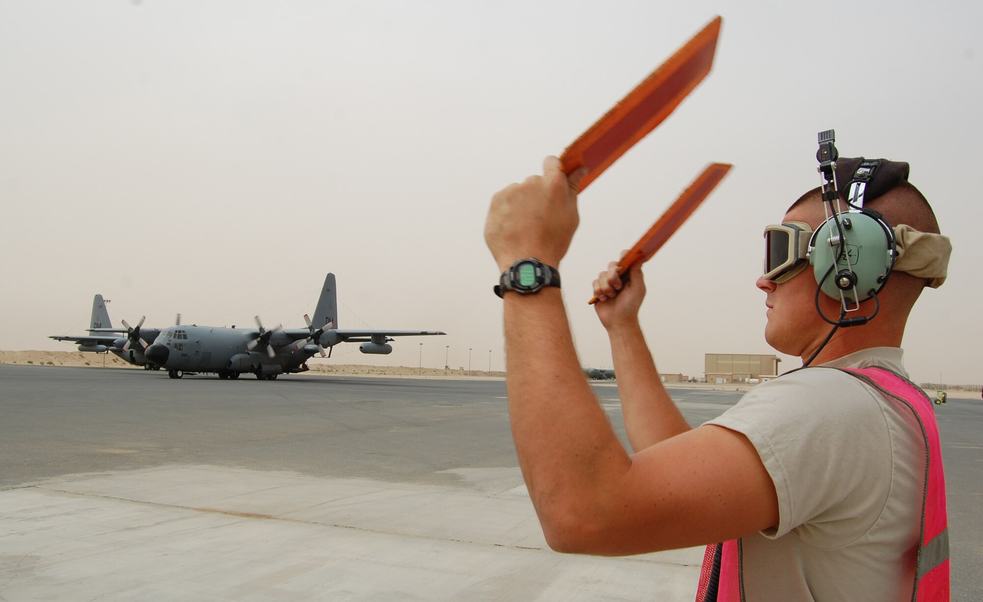 SOUTHWEST ASIA -- Airman Cory Francis, a C-130 crewchief deployed with the 386th Expeditionary Aircraft Maintenance Squadron uses marshalling paddles to direct aircraft commander Capt. Tony Stibral and co-pilot 1st Lt. Corey Hogue returning from a mission March 18, 2008, to their parking spot on the ramp of an air base in the Persian Gulf Region. The pilots and seven other crewmembers from the 43rd Expeditionary Electronic Combat Squadron on board completed the unit’s 2,276th combat sortie capping the Arizona-based unit’s fourth consecutive year deployed supporting the Global War on Terror. Airman Francis is deployed from the 755th AMXS, and the aircrew members from the 55th Electronic Combat Group out of Davis-Monthan Air Force Base. (Air Force photo/Tech. Sgt. Michael O’Connor)