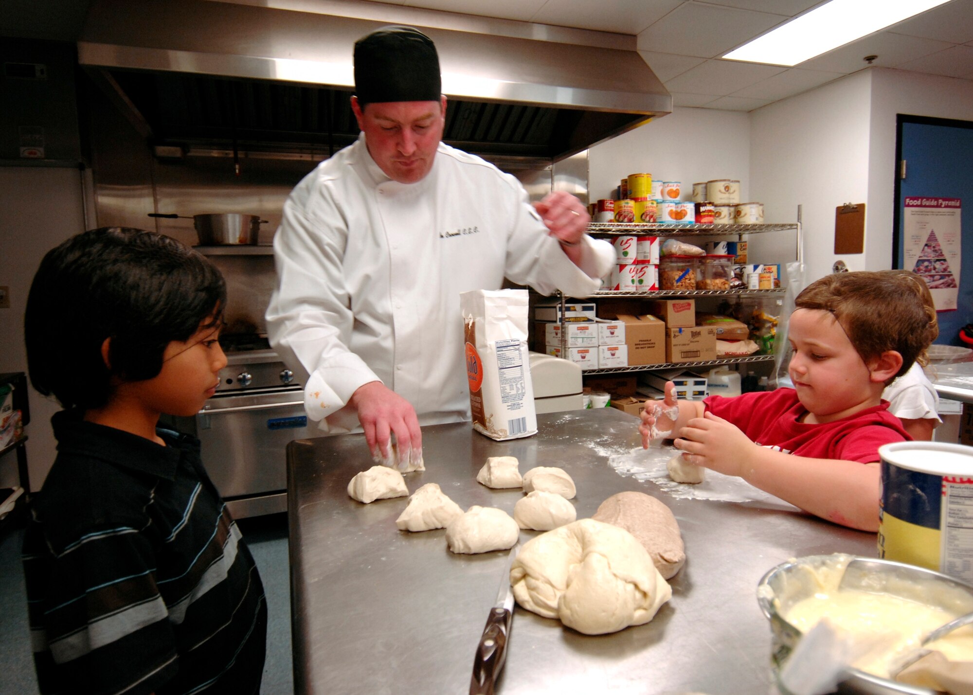 Brian Crowell, husband of Master Sgt Caryl Crowell, teaches kids how to make pizza at a Youth Services cooking class, March 14. (Photo by Lou Hernandez)