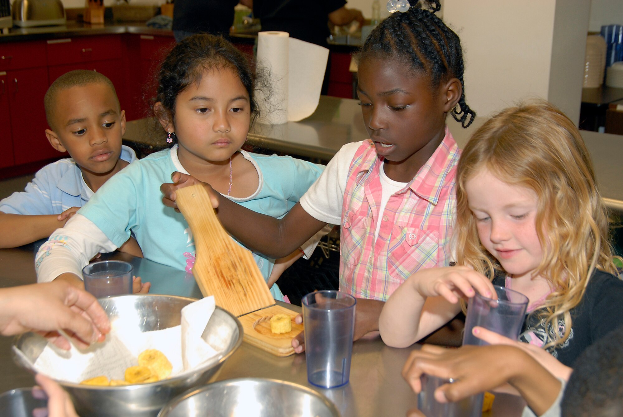 Children learned how to peel, cut, smash and season plantains at a Youth Services cooking class, March 7.  Pictured left to right are: Gabriel Briley, Samantha Arquiza, Emerald Wilson and Kiersten Crowell.  (Photo by Joe Juarez)