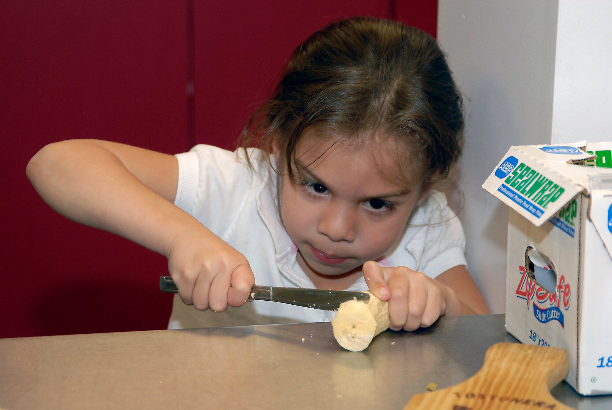 Alexa Montero carefully cuts a plantain at a Youth Services cooking class, March 7. (Photo by Joe Juarez)