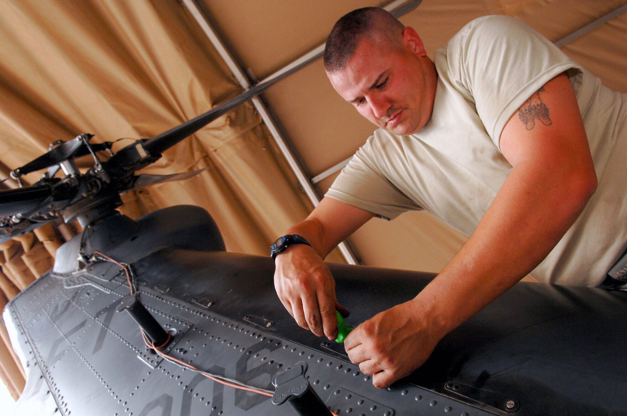 Staff Sgt. Tait Delzer tightens down the drive shaft cover of an HH-60 Pave Hawk helicopter March 12 at Balad Air Base, Iraq.   Sergeant Delzer, a crew chief with the 64th Expeditionary Helicopter Maintenance Unit, performed an inspection on the aircraft after it had been flown 300 hours. During the inspection, all of the panels and covers were removed to facilitate preventative maintenance on the aircraft's systems and equipment. Sergeant Delzer is deployed from Moody Air Force Base, Ga. (U.S. Air Force photo/ Senior Airman Julianne Showalter)