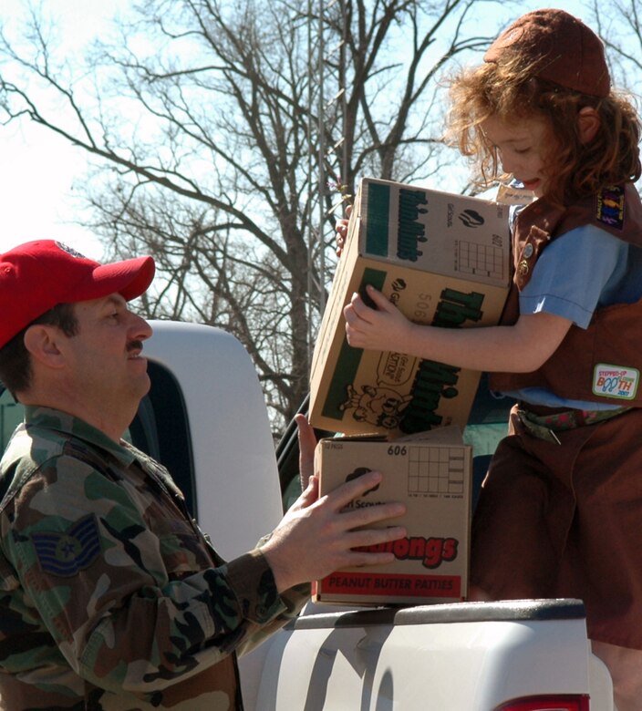 A Brownie Girl Scout member from Troop 26 hands boxes of cookies off to Tech. Sgt. Wendell Ward, 307th RED HORSE member, Wednesday, March 12 at Barksdale AFB. The Scouts of Troop 26, out of Tyler, Texas, recently did their part in supporting the military. Troop 26 collected donations and bought boxes of their own cookies to send to deployed members of the 307 RHS. For this selfless act, Troop 26 earned the Troop to Troop National Badge. (U.S. Air Force photo/Staff Sgt. Ebony Nichols) 
