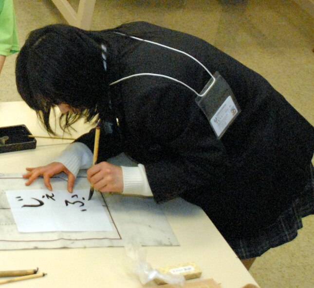 Kanako Abe, a 10th-grader from  Kakuda High School in Japan, uses a special brush and ink to create ‘Shuji,’ Japanese traditional calligraphy March 19 here. As part of the ninth-annual Iwanuma City and city of Dover exchange program, Japanese students taught Dover students and parents about art, cuisine and many other subjects relevant to Japanese culture. (U.S. Air Force photo/Tech. Sgt. Kevin Wallace)