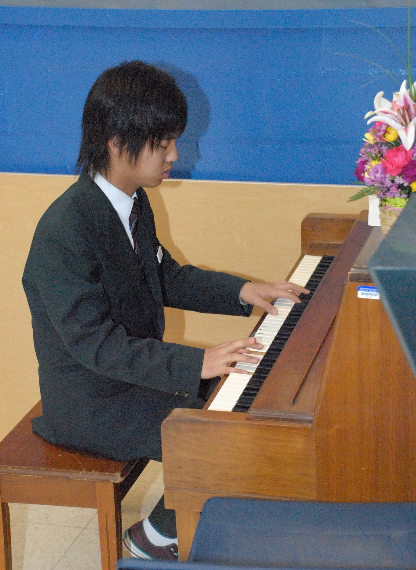 Tomohiro Mukade, a student at Iwanuma City Middle School in Japan, plays the piano as nine fellow Iwanuma students sing their school song to Dover Air Base Middle School students and parents at the DAB Middle School auditorium March 19. As part of the ninth-annual Iwanuma City and city of Dover exchange program, Japanese students taught Dover students and parents about music, art and many other subjects relevant to Japanese culture. (U.S. Air Force photo/Tech. Sgt. Kevin Wallace)