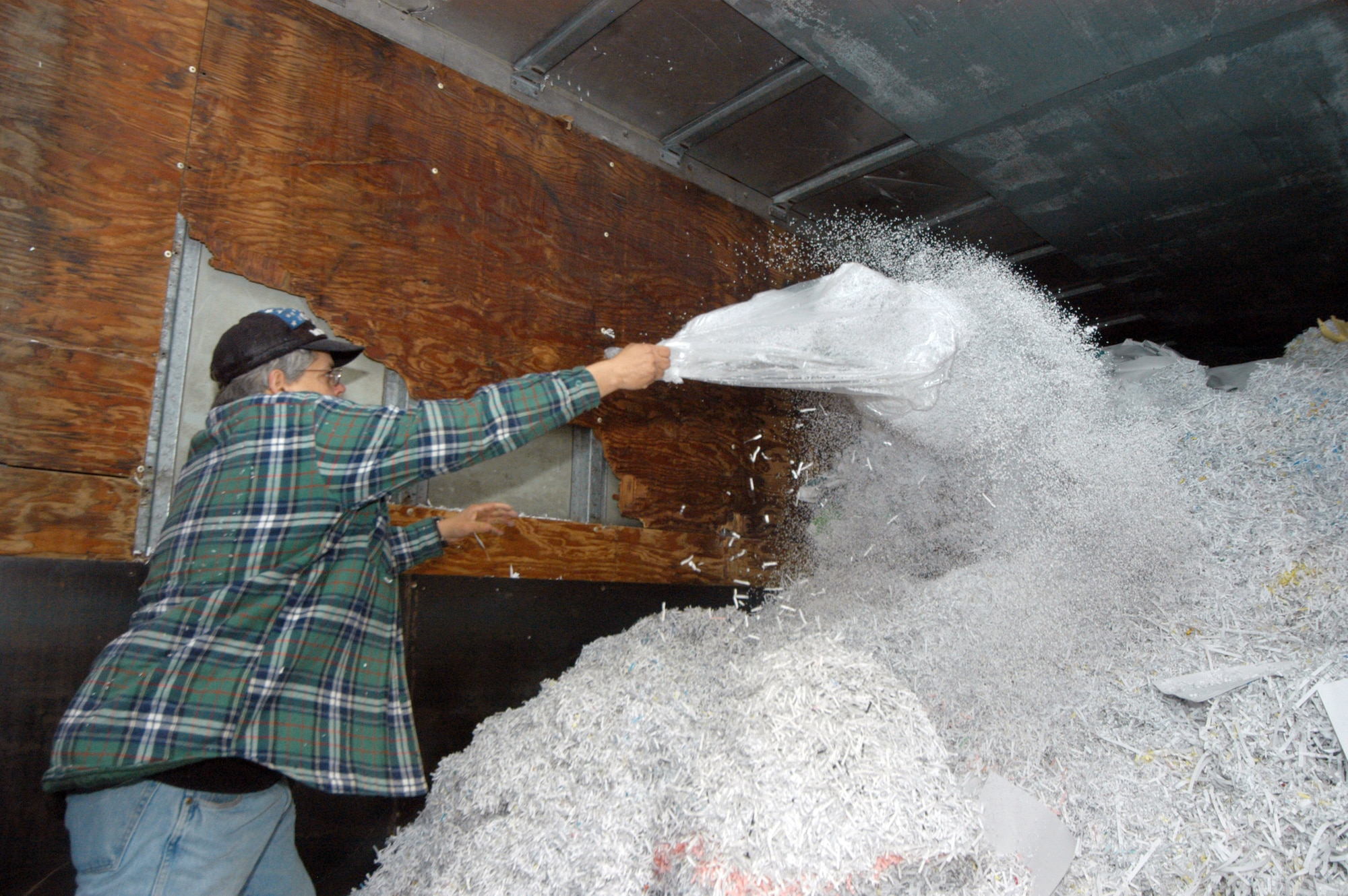 Allen Spence empties shredded paper that will be used to produce other products into a trailer.  U. S. Air Force photo by Sue Sapp  