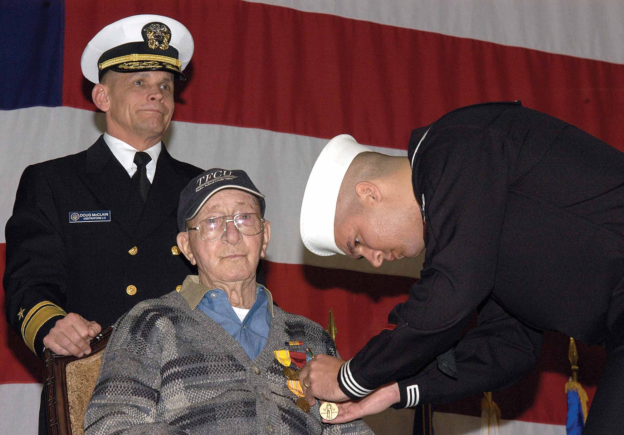 Petty Officer 2nd Class Adam Kishman pins the World War II Victory Medal on Navy veteran Loyd Carter’s sweater during a March 14 ceremony in the Center for Naval Aviation Technical Training bay here. Petty Officer Kishman and Rear Adm. Doug McClain, director of global operations, U.S. Strategic Command, awarded seven medals to the Petty Officer Third Class who survived the Pearl Harbor attack aboard the USS California and the sinking of the USS Indianapolis.  Petty Officer Kishman learned of the veteran’s service and was praised for arranging the long-overdue awards ceremony. (Air Force photo by Margo Wright)