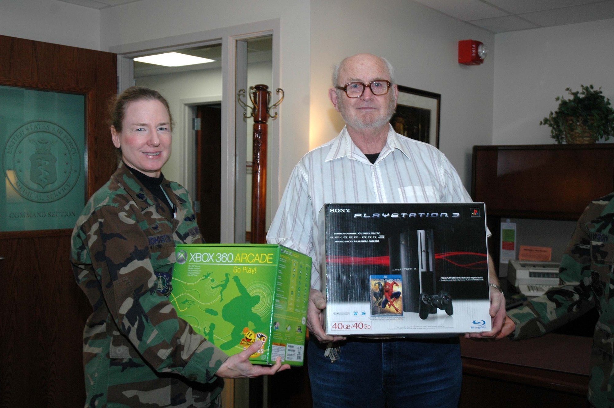 Lt. Col. Martha Johnston, 341st Medical Operations Squadron commander and head of the Air Force Ball committee, presents retiree Donald Parson an XBox 360 and a Playstation 3. Mr. Parson was selected in a raffle that served as a fundraiser for the Air Force Ball. The raffle sales raised more than $1,200. (U.S. Air Force photo/Airman 1st Class Emerald Ralston)