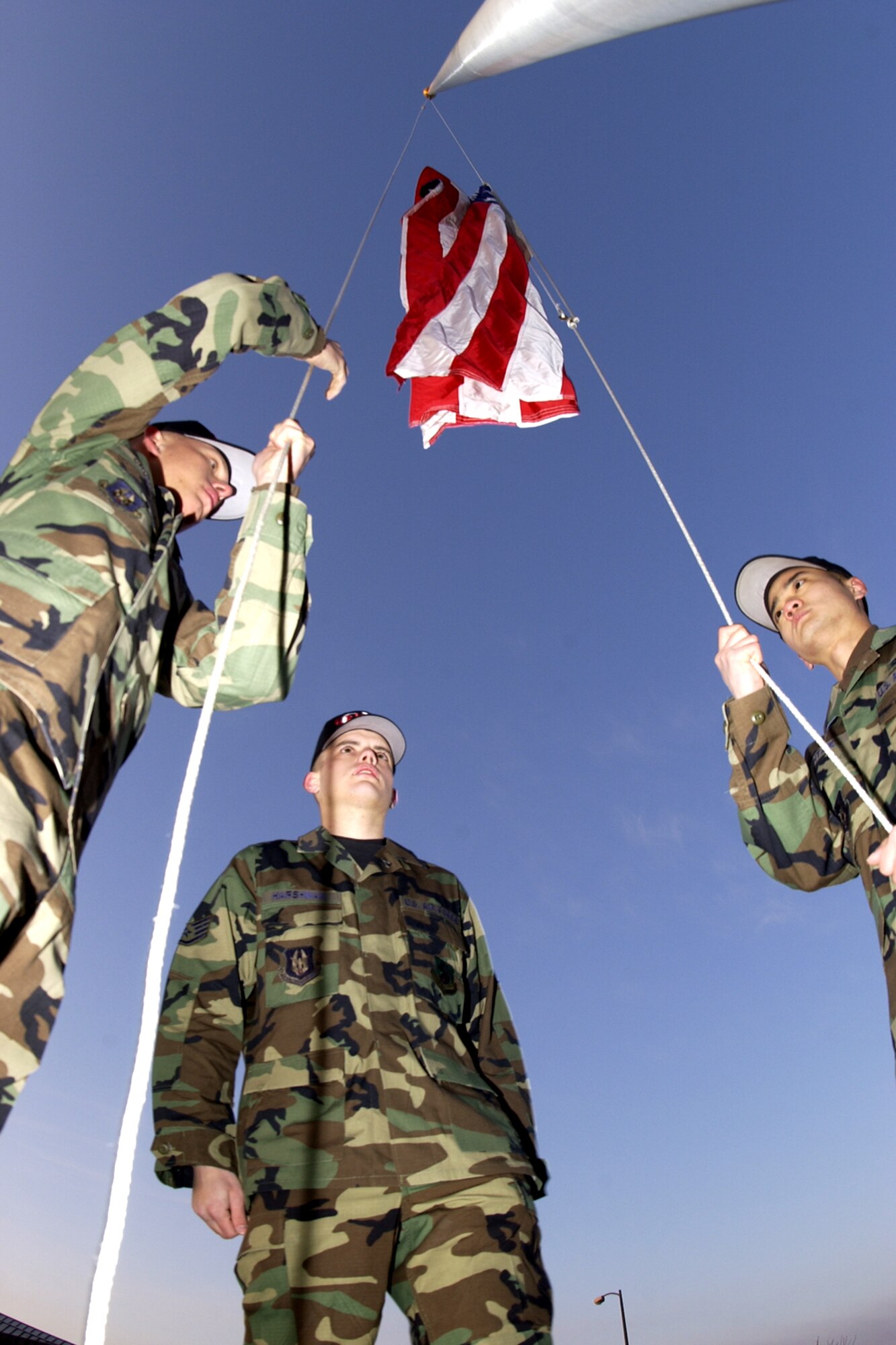 GRISSOM AIR RESERVE BASE, Ind., -- Grissom Civil Engineers, from left, Senior Airman Matthew Crummel, Staff Sgt. Daniel Harshman, and Senior Airman Andrew Htaik, raise the flag for the first time at Grissom's new base flag pole, located near the intersection of Grissom Avenue and Boxcar Street. (U.S. Air Force photo/Tech. Sgt. Doug Hays)