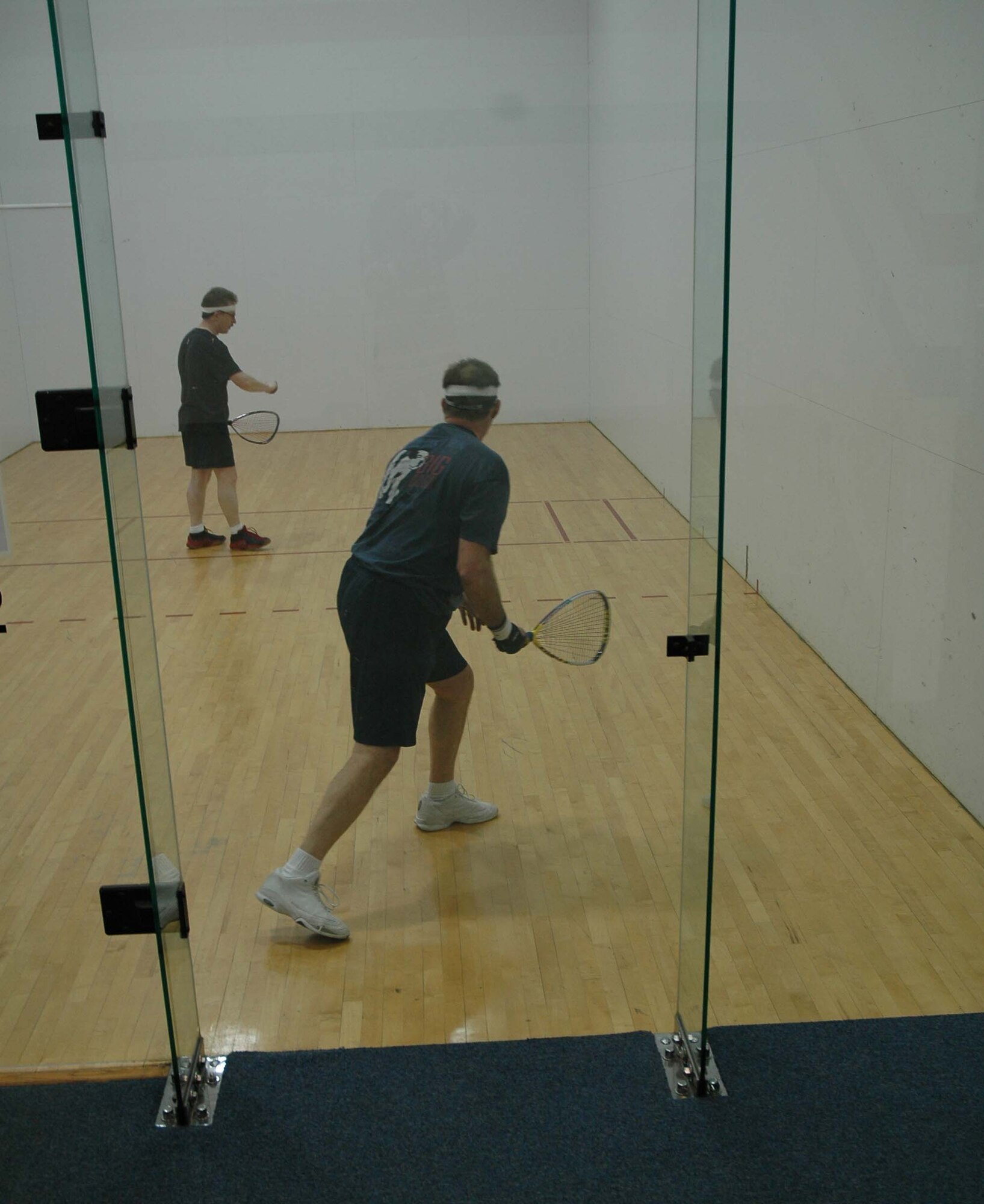 Jerry Kain (background) gets ready to return a serve from a fellow racquetball player during a lunchtime aerobic workout as part of his Largest Loser exercise routine. Mr. Kain plays the game three times a week and supplements on the other days with spinning classes. (U.S. Air Force photo/Valerie Mullett)