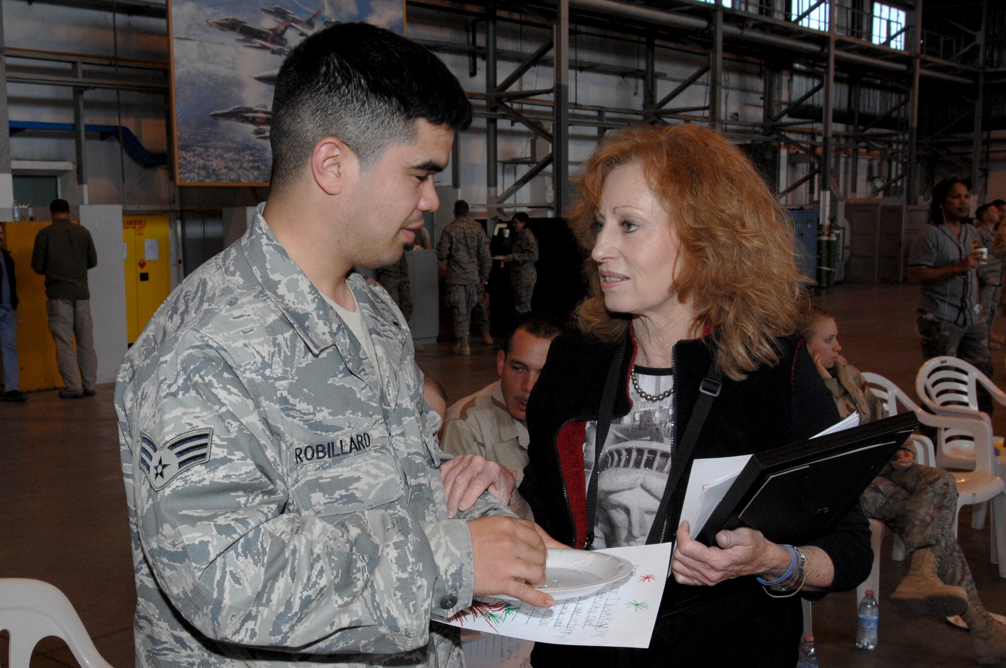 Virginia Winegar, a fifth grade teacher from Texas, hands a letter to Senior Airman Jeremiah Robillard at Aviano Air Base, Italy, March 20.  Airman Robillard and other troops received letters from Virginia's students during their stop at Aviano on their way home from deployment.  (U.S. Air Force photo/Airman 1st Class Tabitha M. Mans)

