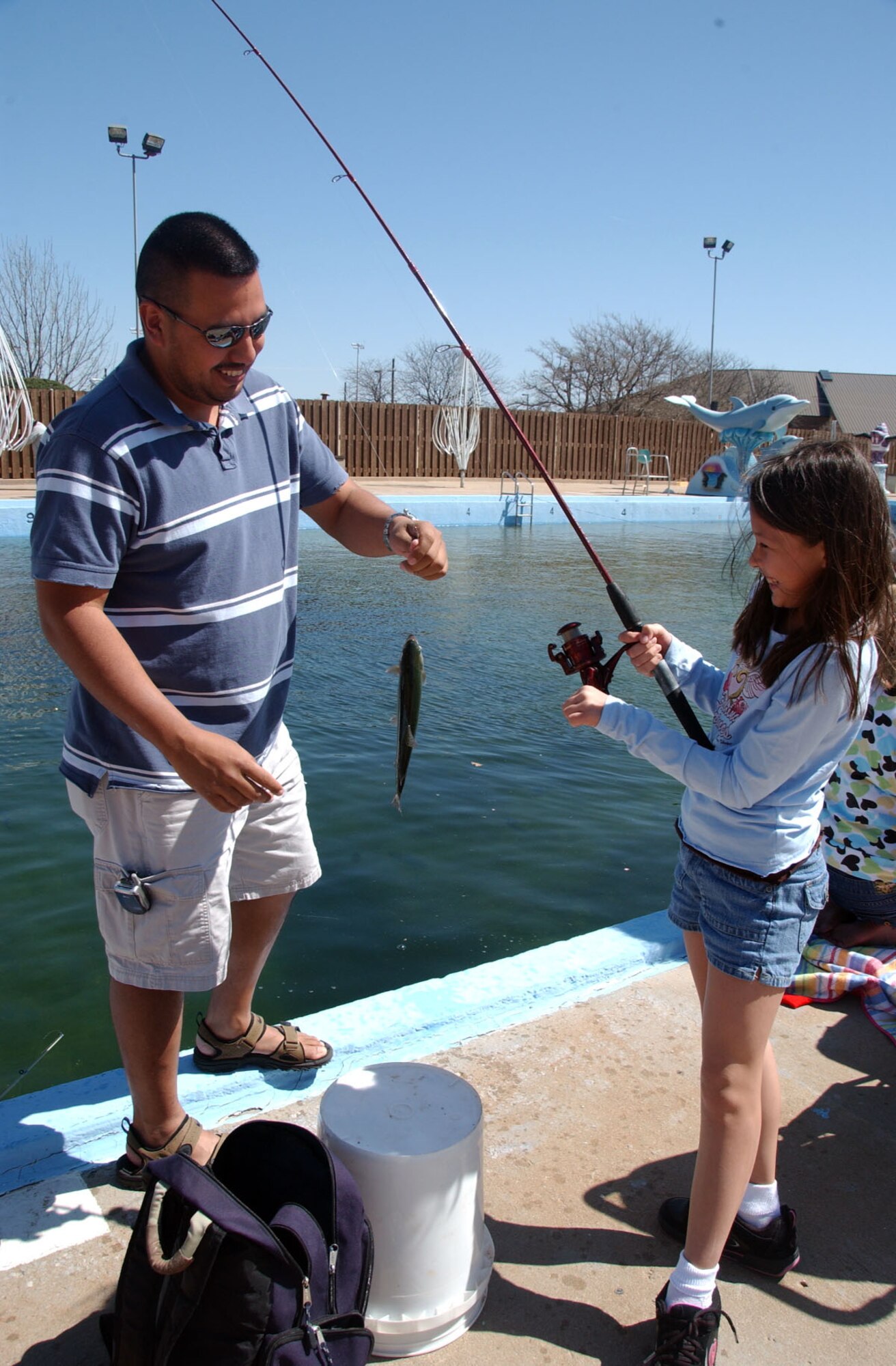 ALTUS AIR FORCE BASE, Okla. -- Julio Cedillo helps his step daugther, Cheyenne Berenz, 8, with the fish she caught during the opening day of the 14th Annual Outdoor Recreation Trout Derby at the Base Pool March 20. (U.S. Air Force photo by Senior Airman Clinton Atkins)