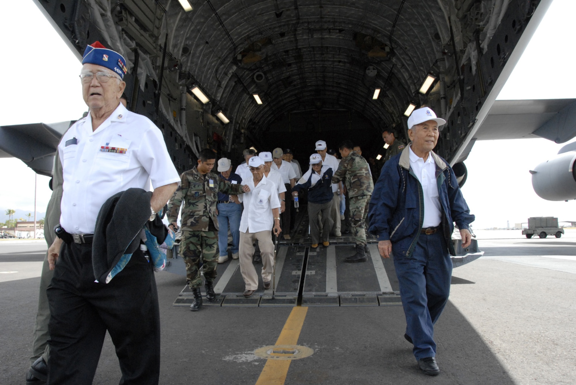 Veterans from the 442nd Regimental Combat Team and the 100th Infantry Battalion exit the back of the "Spirit of Go For Broke" after getting a 45-minute flight around some of the Hawaiian Islands. The "Spirit of Go For Broke," one of Hickam'Air Force Base's C-17 Globemaster III aircraft, was named in honor of the men and their motto. The soldiers of "Go For Broke" were volunteers of second generation Japanese Americans and the unit was one of the most highly decorated World War II combat units. (U.S. Air Force photo/Tech. Sgt. Tom Czerwinski) 
