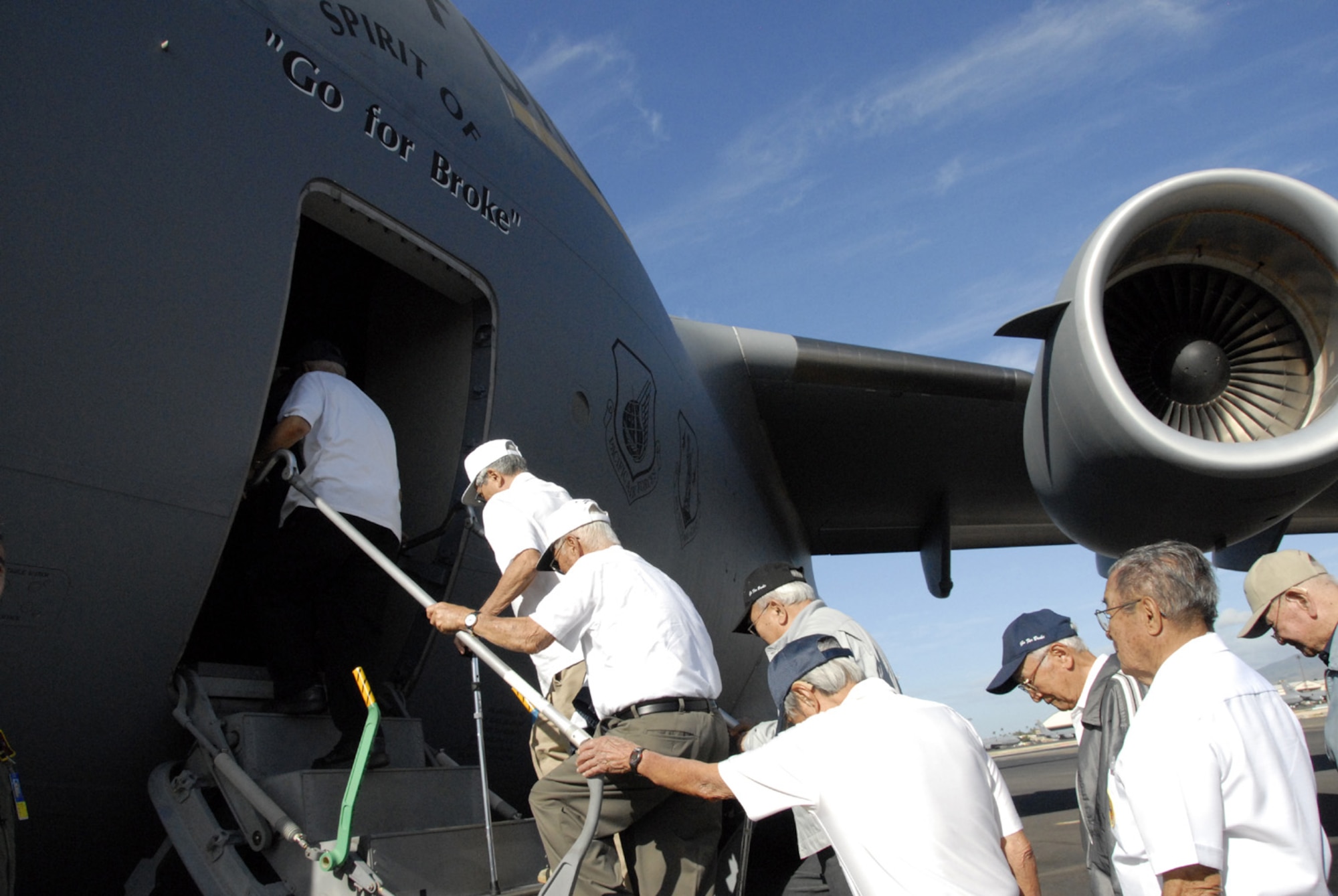 Veterans of the famed 442nd Regimental Combat Team and the 100th Infantry Battalion climb on board the "Spirit of Go for Broke" March 13 at Hickam Air Force Base, Hawaii. After waiting for more than a year and a half, the men for whom it was named finally get their ride on the C-17 Globemaster III aircraft. They took to the skies for a 45-minute flight around some of the Hawaiian Islands. (U.S. Air Force photo/Tech. Sgt. Tom Czerwinski) 