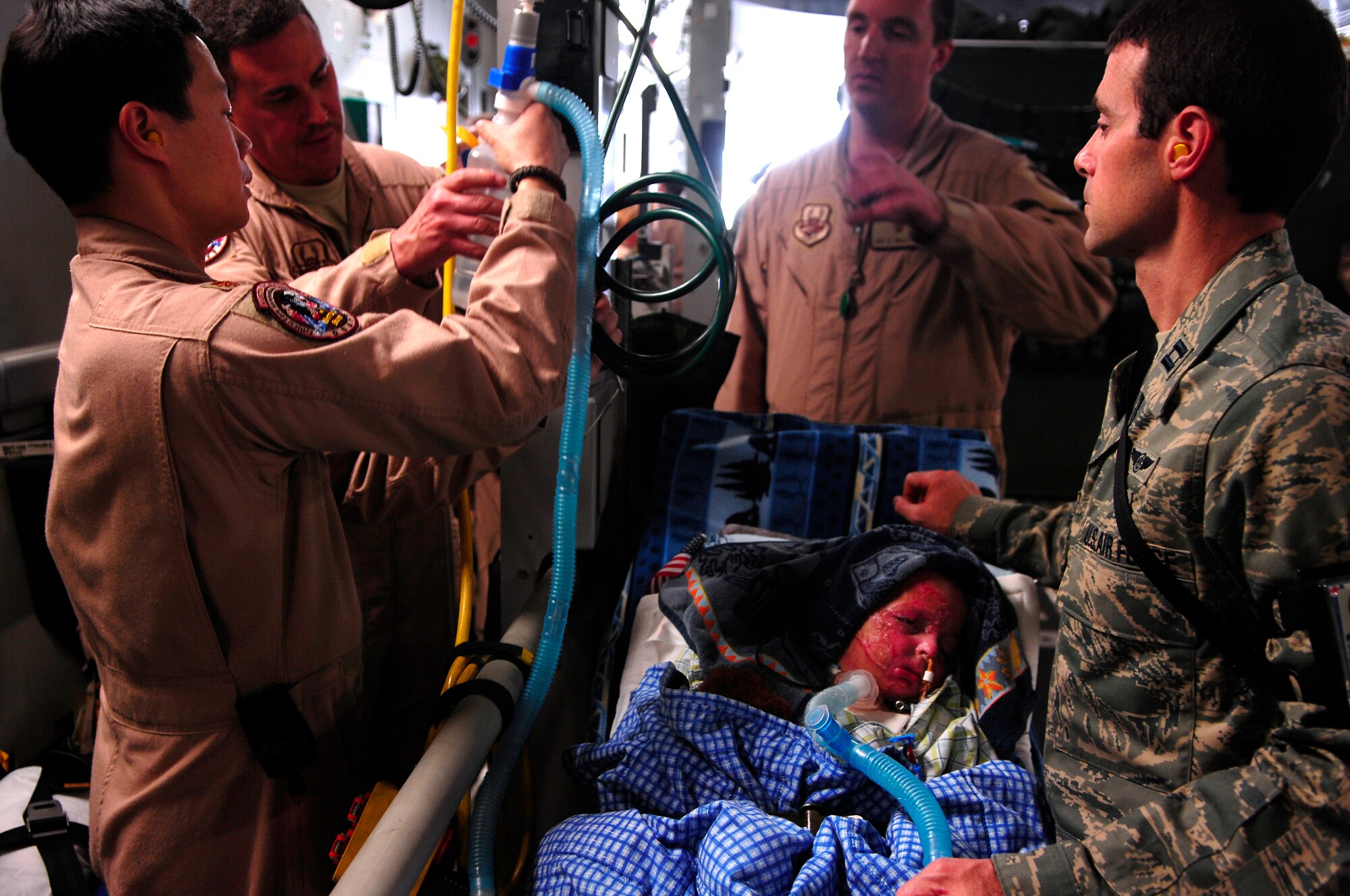 BALAD AIR BASE, Iraq -- Members of the 332nd Expeditionary Aeromedical  Evacuation Flight Critical Care Transportation Team prepare 3-year-old Iraqi burn victim Al Amreeki for a flight to the United States March 21. Al Amreeki was only given 48 hours to live after being burned in a fire. Two months later he and his mother are being transported back to the United States for further treatment and physical therapy. U.S. Air Force Photo/Tech. Sgt. Jeffrey Allen 