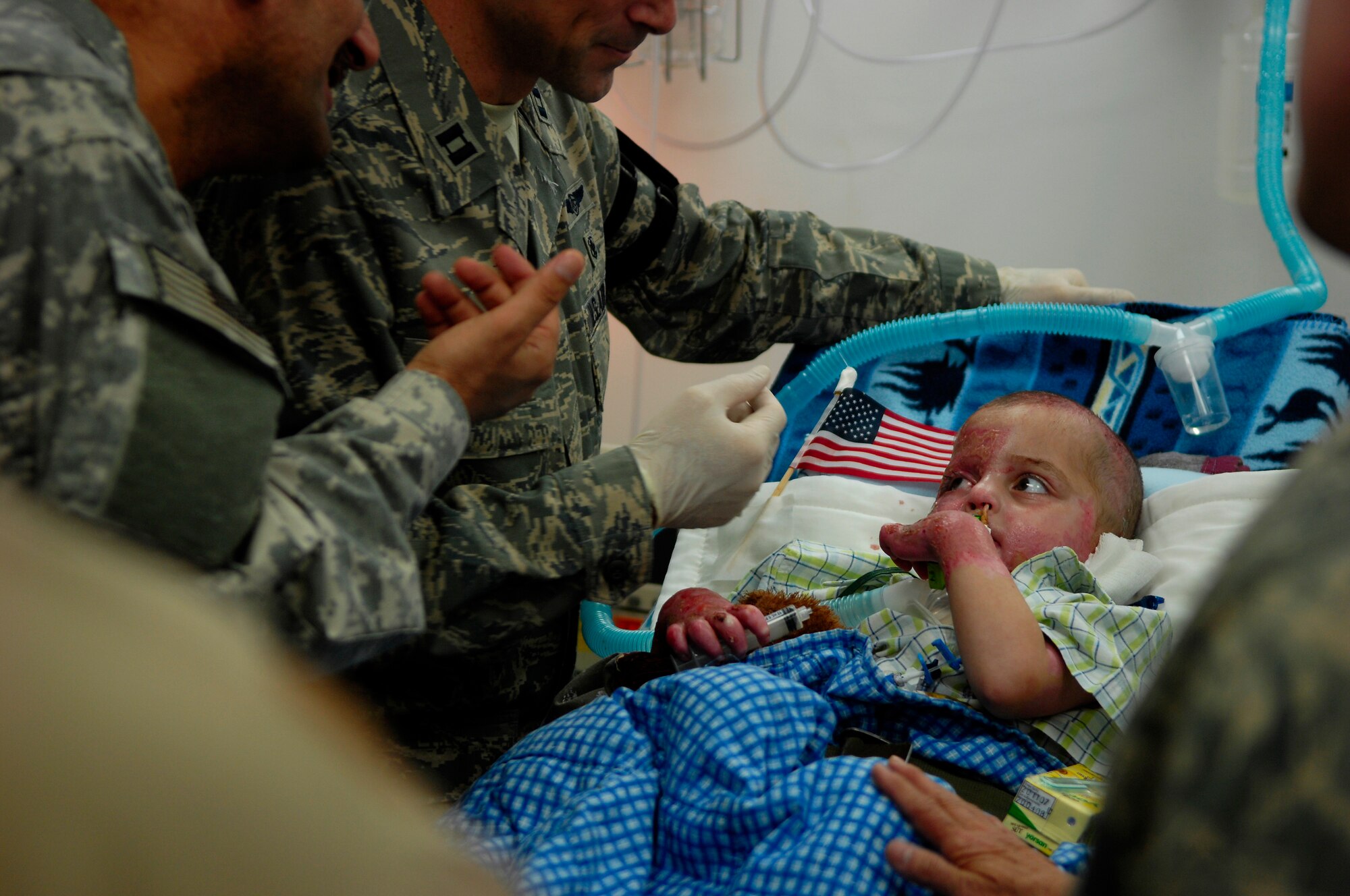 BALAD AIR BASE, Iraq -- Al Amreeki, a 3-year-old Iraqi burn interacts with his nurse and interpreter while at the Air Force Theater Hospital March 21. Al Amreeki was only given 48 hours to live after being burned in a fire.  Two months later he and his mother are being transported back to the United States for further treatment and physical therapy. (U.S. Air Force Photo/Tech. Sgt. Jeffrey Allen)