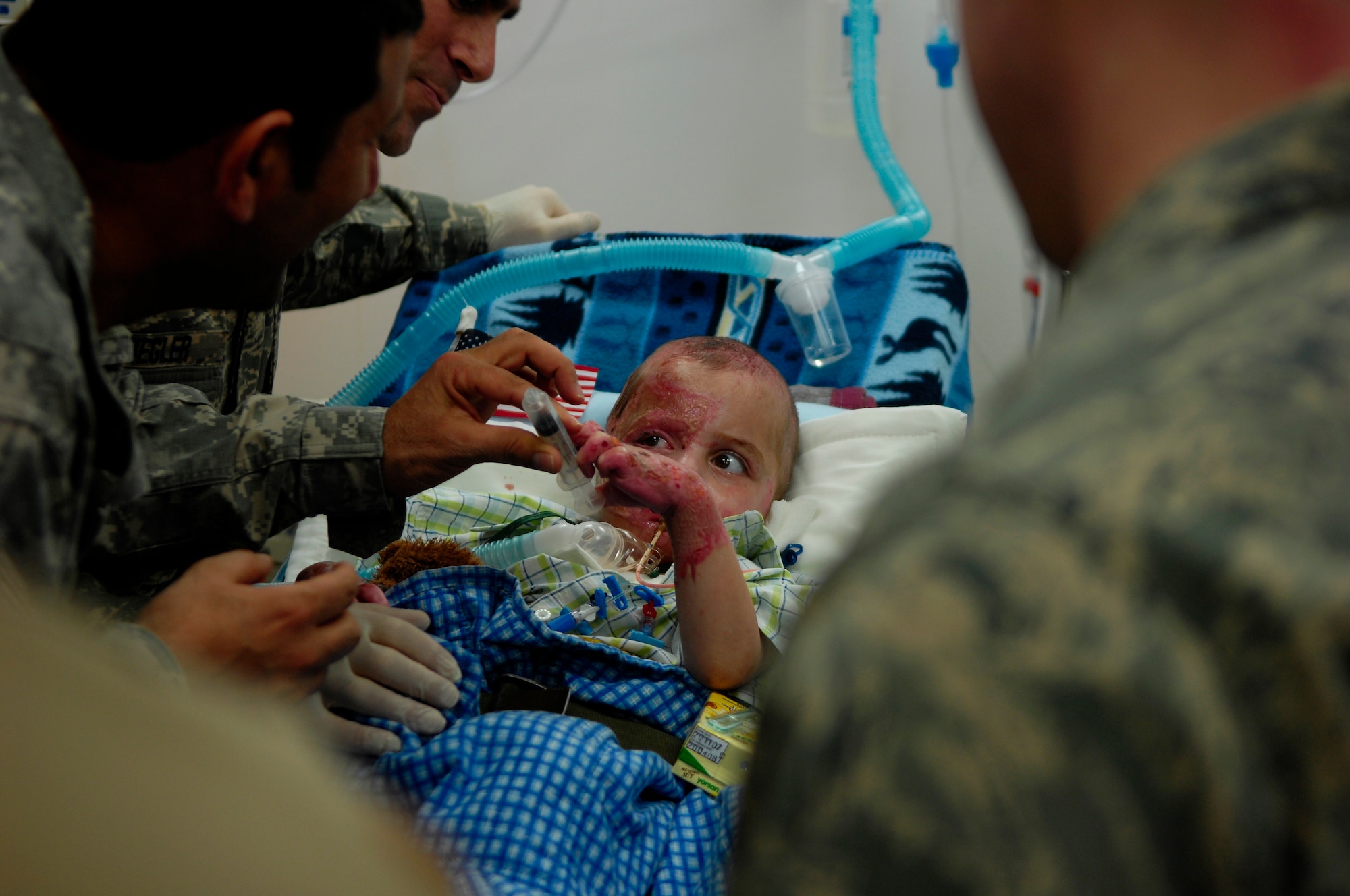 BALAD AIR BASE, Iraq -- Al Amreeki, a 3-year-old Iraqi burn victim plays with a make shift squirt gun while at the Air Force Theater Hospital March 21. Al Amreeki was only given 48 hours to live after being burned in a fire.  Two months later he, and his mother, are being transported back to the United States for further treatment and physical therapy. (U.S. Air Force Photo/Tech. Sgt. Jeffrey Allen)