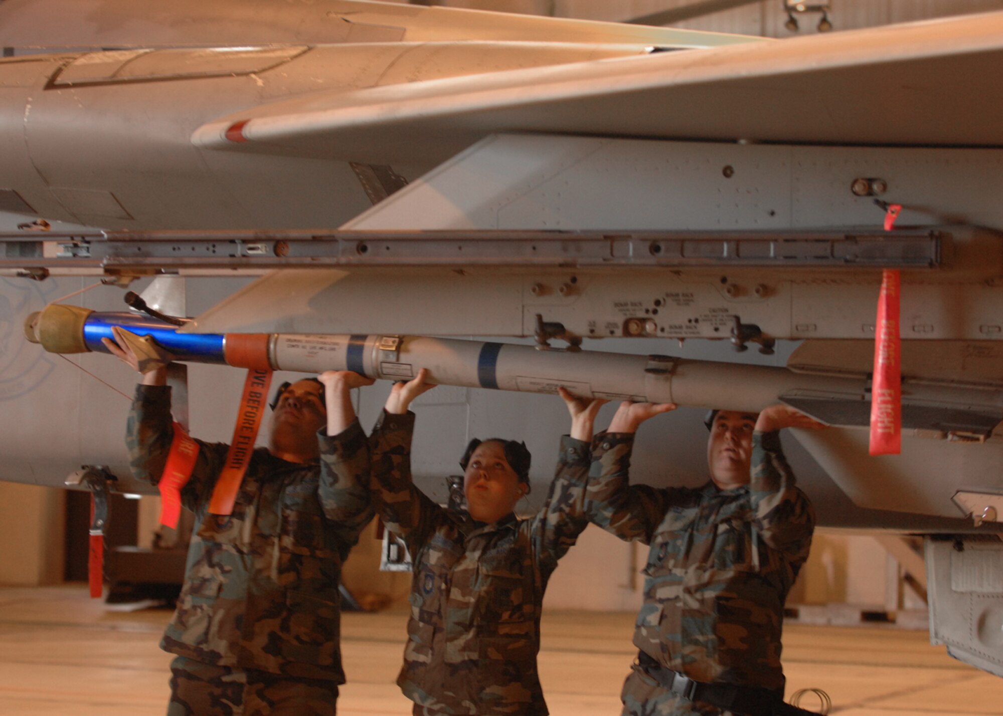 Staff Sgt. William Cole, Senior Airman Daniel Serrano and Airman 1st Class Kayla Gasaway, 493rd Aircraft Maintenance Unit, lift a munition up to the underside of an F-15 C Eagle's wing. Their crew, Crew 75, won the annual weapons load crew competition held at RAF Lakenheath March 14. The competition is between four quarterly winners for the title of the best in the wing out of 47 weapons load crews. (U.S. Air Force photo by Airman 1st Class John Easterling)