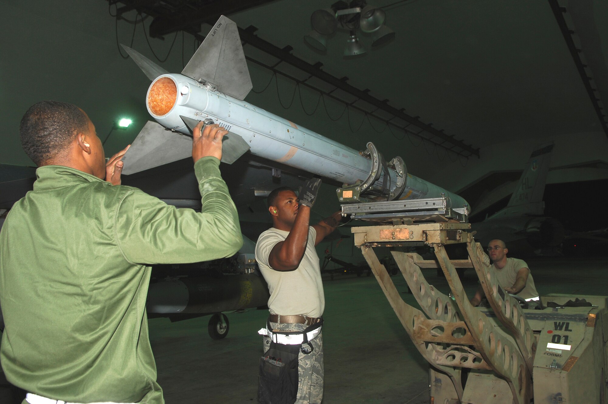 BALAD AIR BASE, Iraq -- From left, Airman 1st Class Ray Williams, Staff Sgt. Corey Smith and Airman 1st Class John Wheatley, all armament systems specialists assigned to the 332nd Expeditionary Aircraft Maintenance Squadron Viper Aircraft Maintenance Unit, load a missile onto the wing of an F-16 Fighting Falcon here, March 13. Each crew is comprised of three individuals, a supervisor, an assistant and a driver. All three Airmen are deployed from Hill Air Force Base, Utah. (U.S. Air Force photo/ Staff Sgt. Mareshah Haynes)