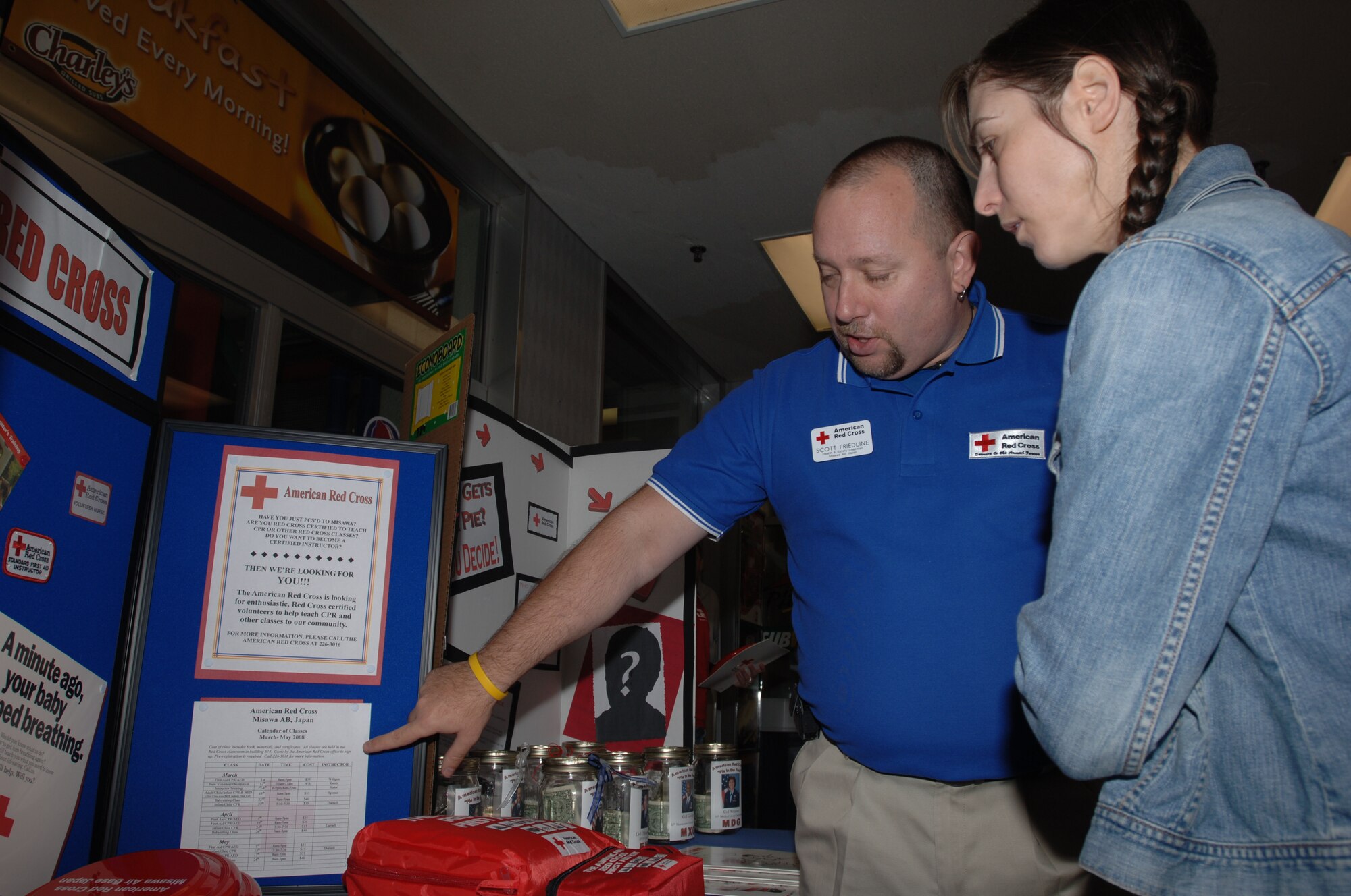 MISAWA AIR BASE, Japan -- Scott Friedline, Red Cross health and safety chairman, explains the functions available at the Red Cross to Jeanette Goodman near the commissary March 20, 2008.  The Red Cross relies on volunteers to function successfully and is located in building 674.  (U.S. Air Force photo by Senior Airman Robert Barnett)