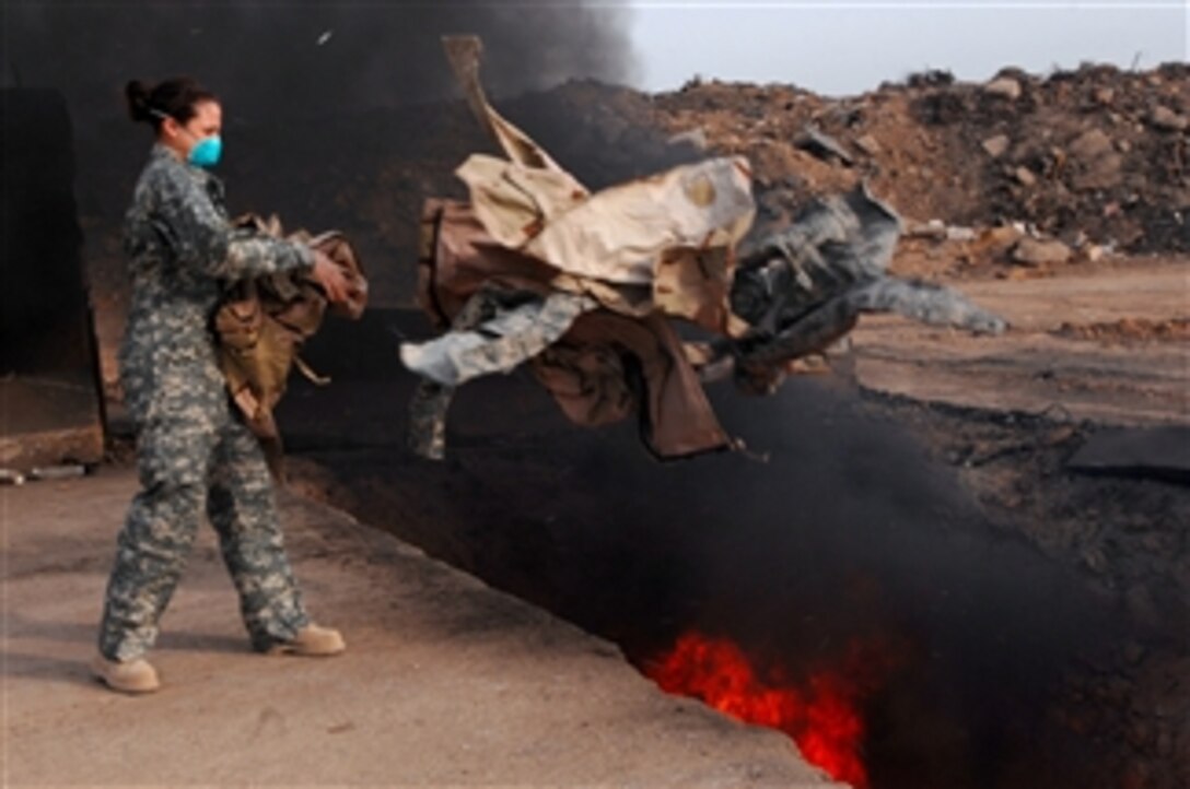 U.S. Air Force Senior Airman Frances Gavalis, 332nd Expeditionary Logistics Readiness Squadron equipment manager, tosses unserviceable uniform items into a burn pit at Balad Air Base, Iraq, on March 10, 2008.  Military uniform items turned in must be burned to ensure they cannot be used by opposing forces.  