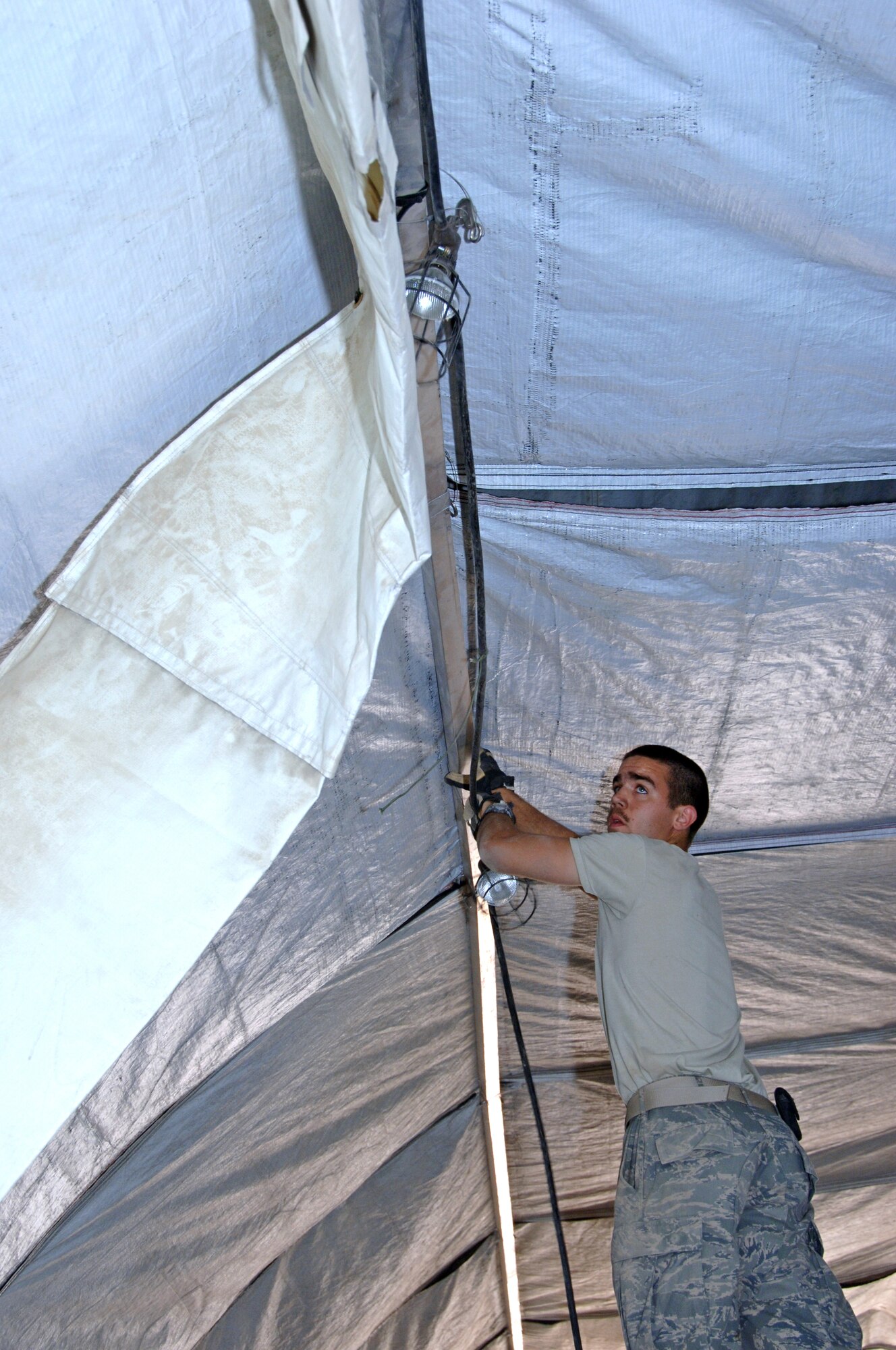 ALI BASE, Iraq -- Airman 1st Class Scott Brown, 407th Air Expeditionary Group member, strings tent lights in the temporary fitness facility March 21.  The temporary shelter is in preparation for a new 12,000 square foot center.  Airman Brown is an electrical systems apprentice deployed from Eielson AFB, Alaska.  (U. S. Air Force photo / Tech. Sgt. Sabrina Johnson)