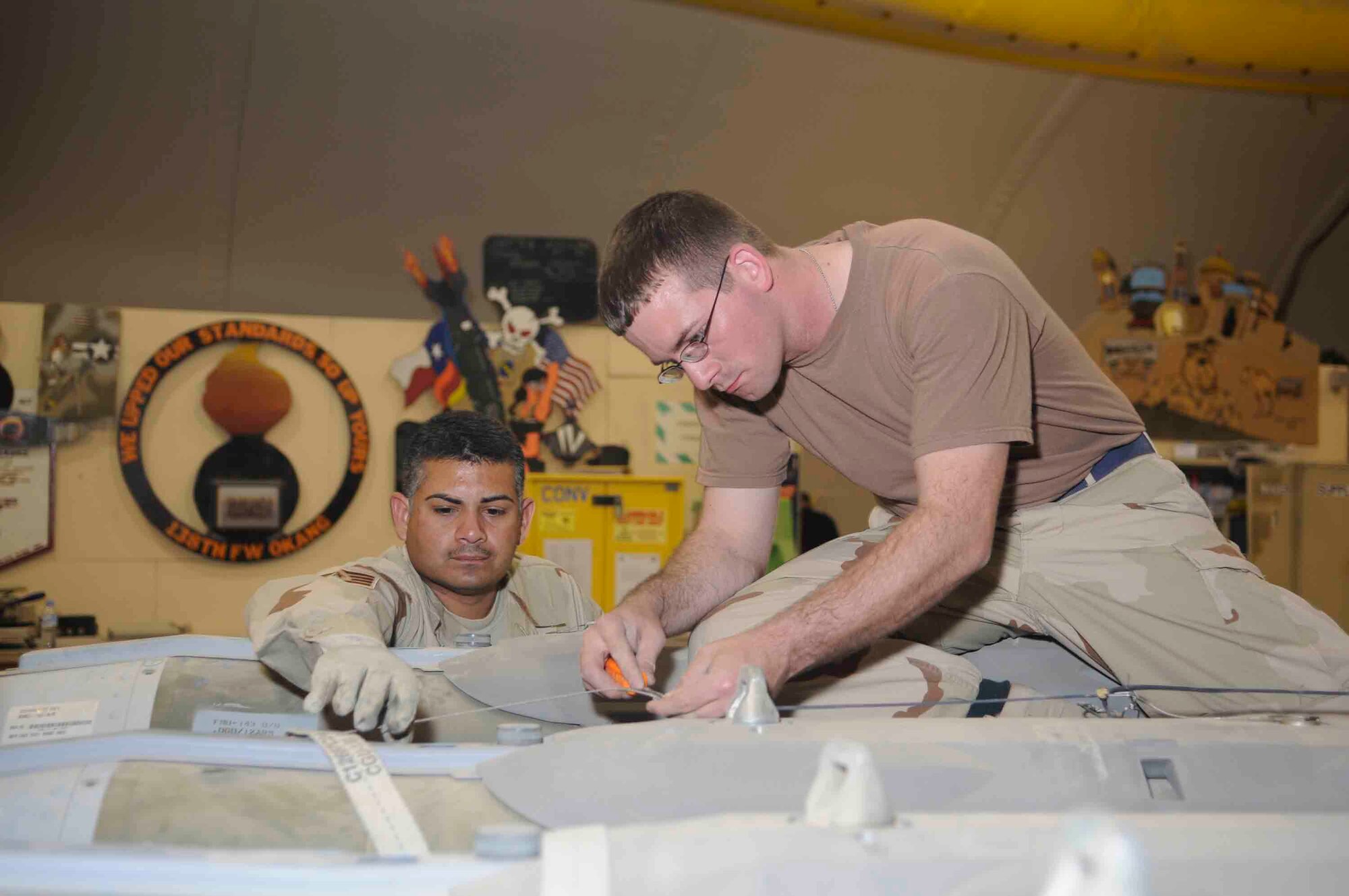 Staff Sgt. Antonio Lozano (left) and Airman 1st Class Shawn Monteer (right) and connect lanyard to a fuse. Connecting lanyard is important to ensure the bomb works without flaw.  (U.S. Air Force photo/Tech. Sgt. Johnny Saldivar)